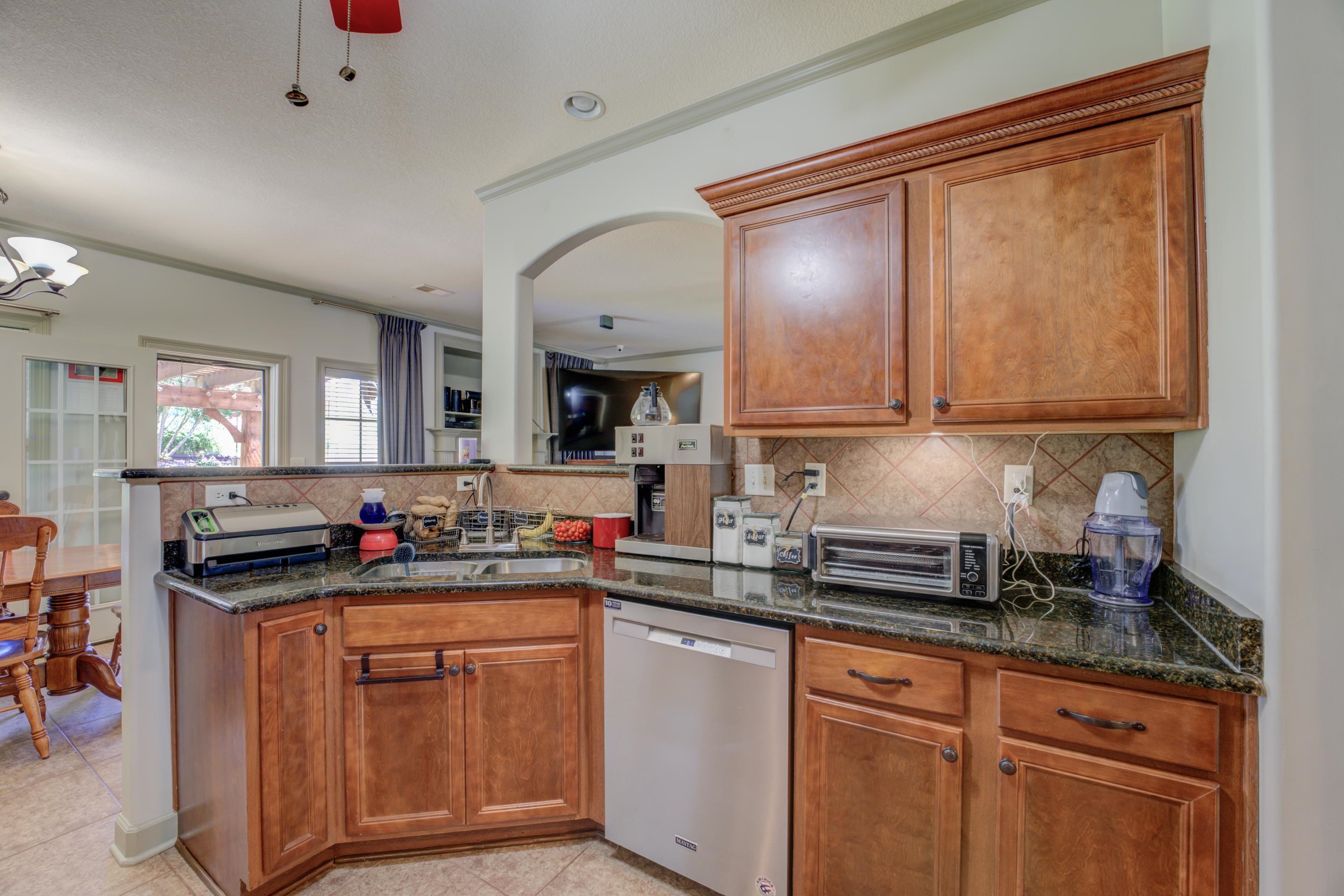 Kitchen with light tile flooring, granite counters, stainless steel appliances, breakfast bar, backsplash, and breakfast area.