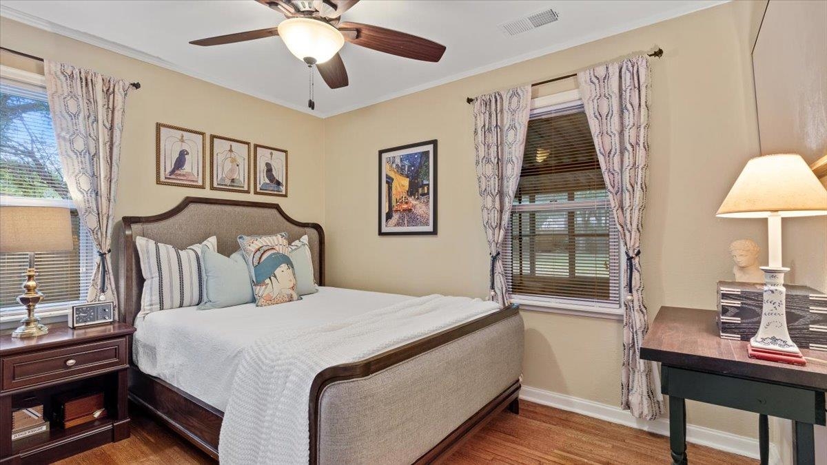 Bedroom with dark hardwood / wood-style flooring, ceiling fan, and crown molding