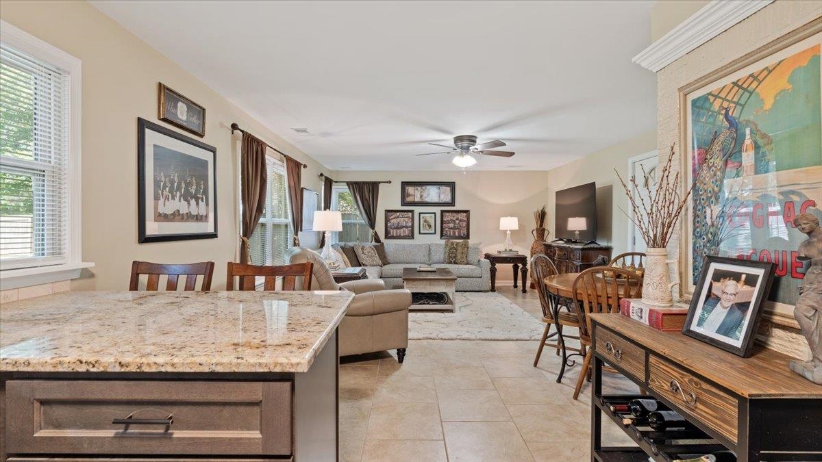 Interior space featuring light tile patterned floors, a healthy amount of sunlight, ceiling fan, and light stone counters