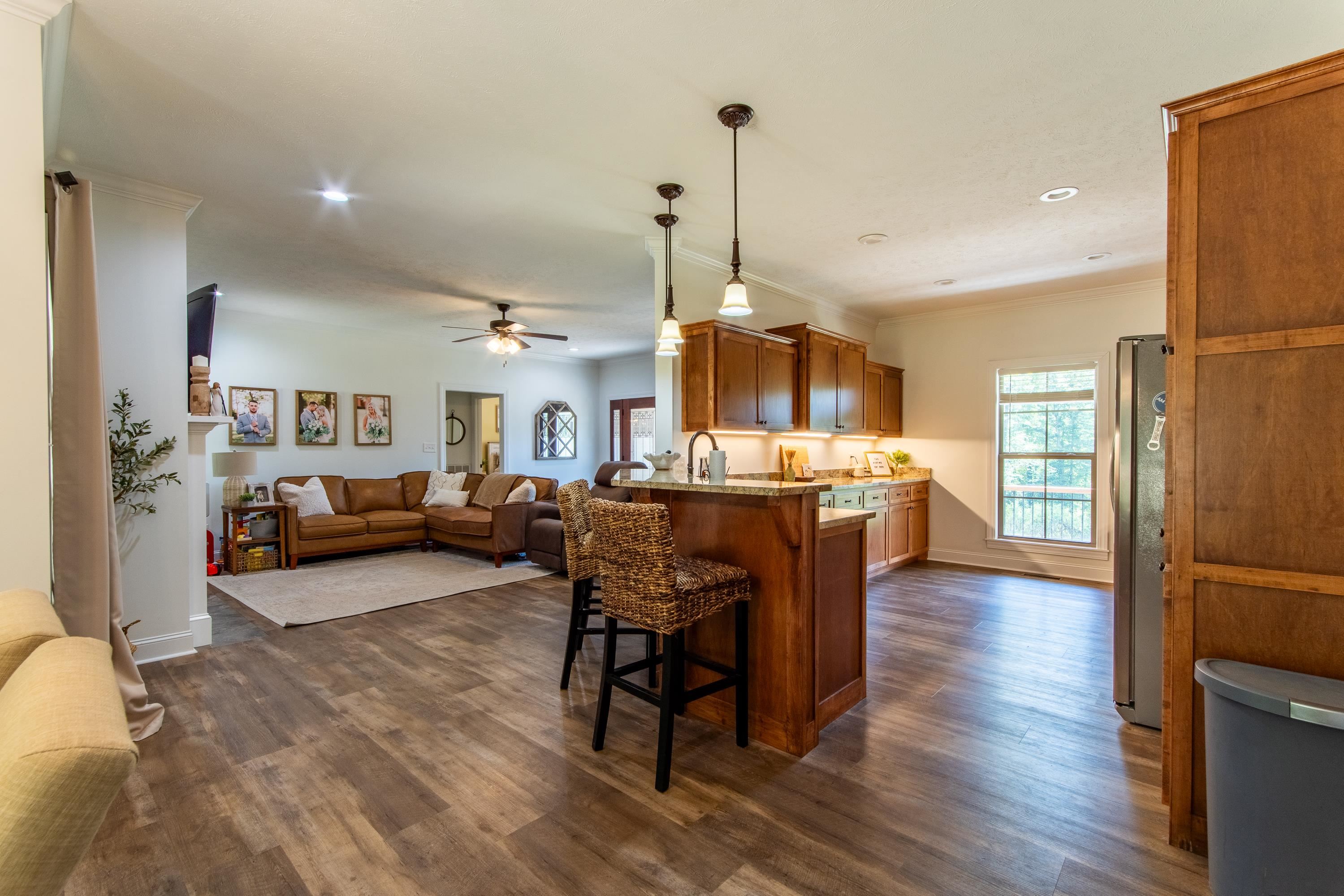 Kitchen featuring a breakfast bar, stainless steel refrigerator, dark wood-type flooring, ceiling fan, and hanging light fixtures