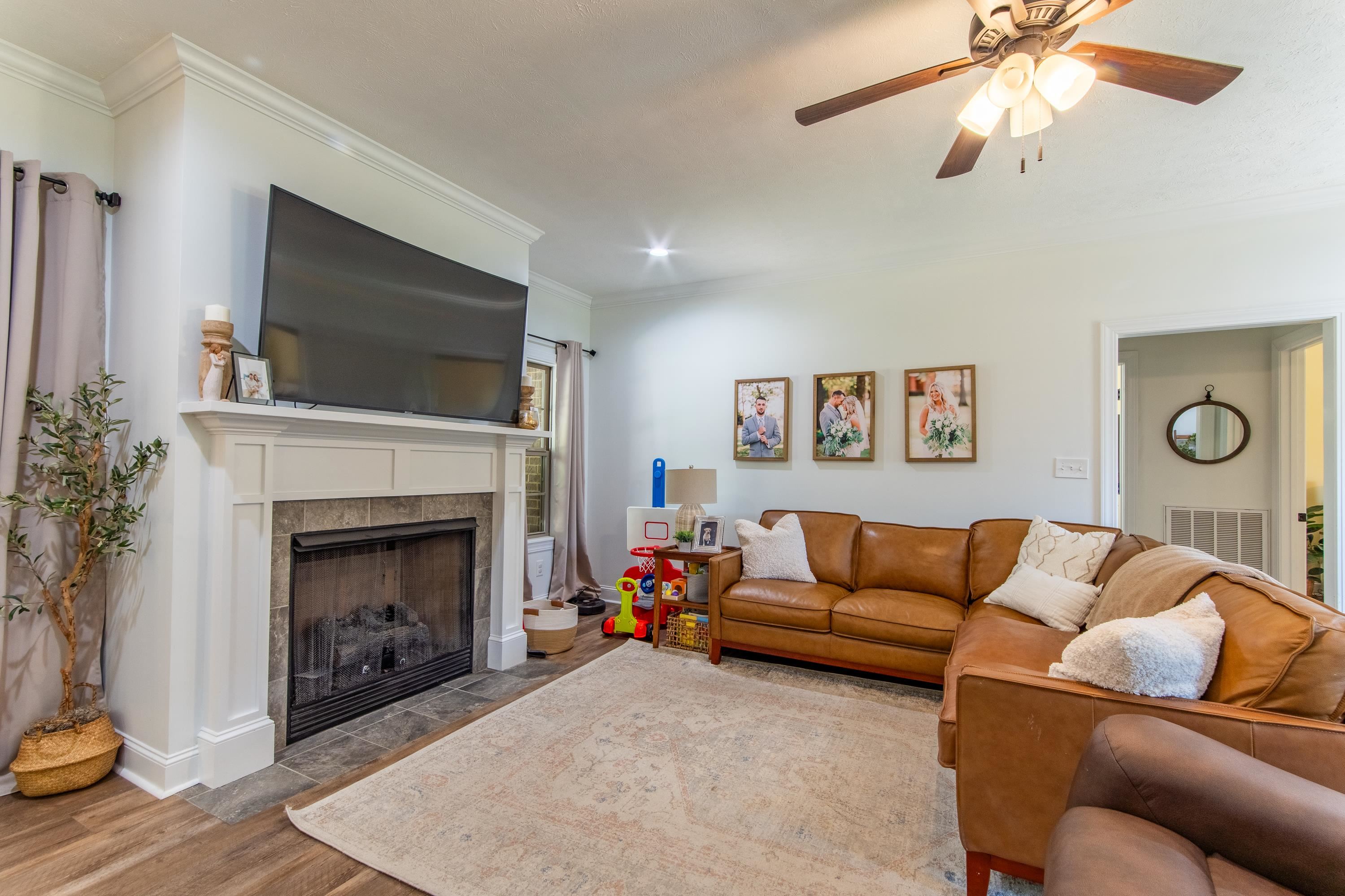 Living room with a fireplace, ornamental molding, hardwood / wood-style floors, and ceiling fan