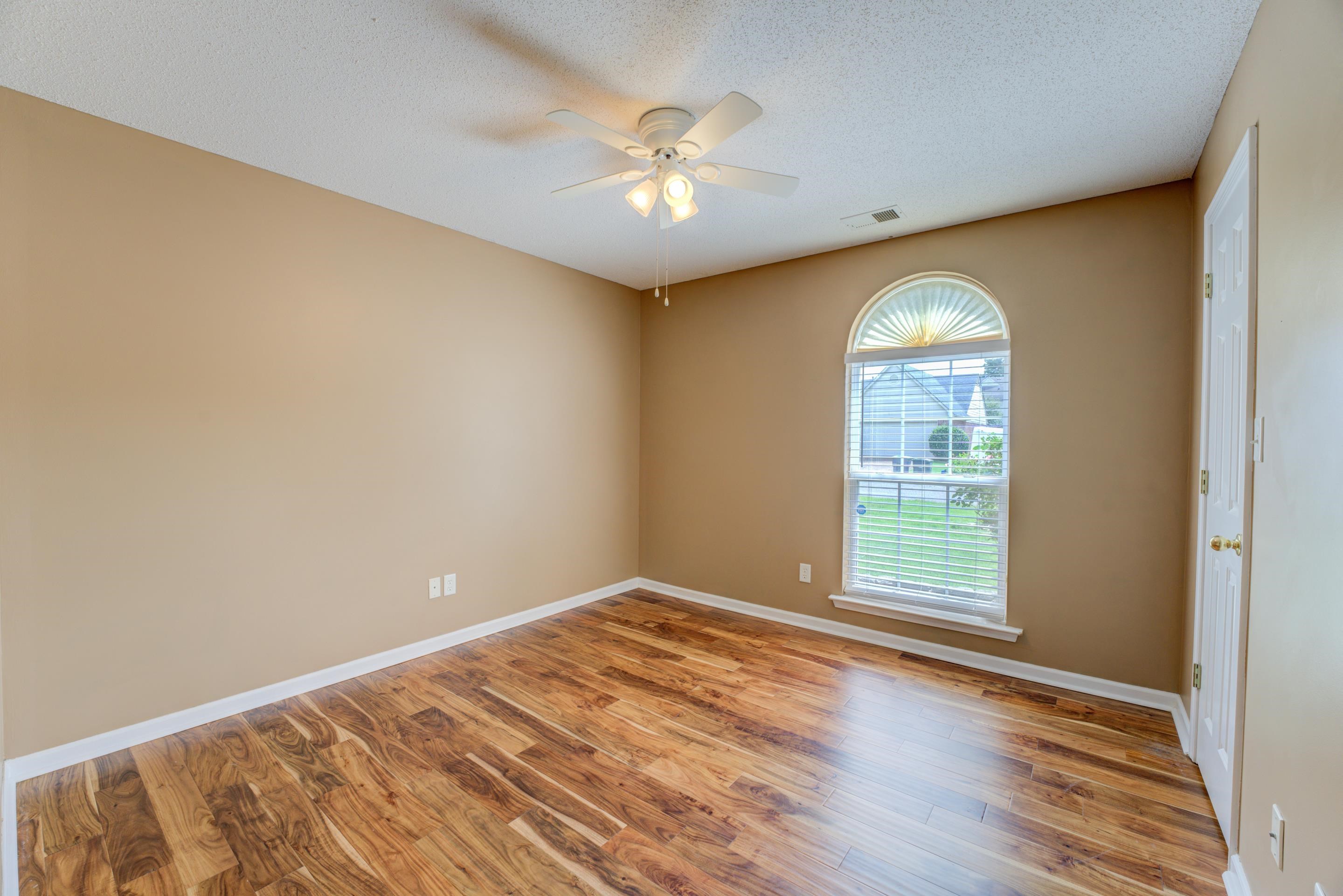 The third bedroom features wood flooring, closet, arched window, and ceiling fan.