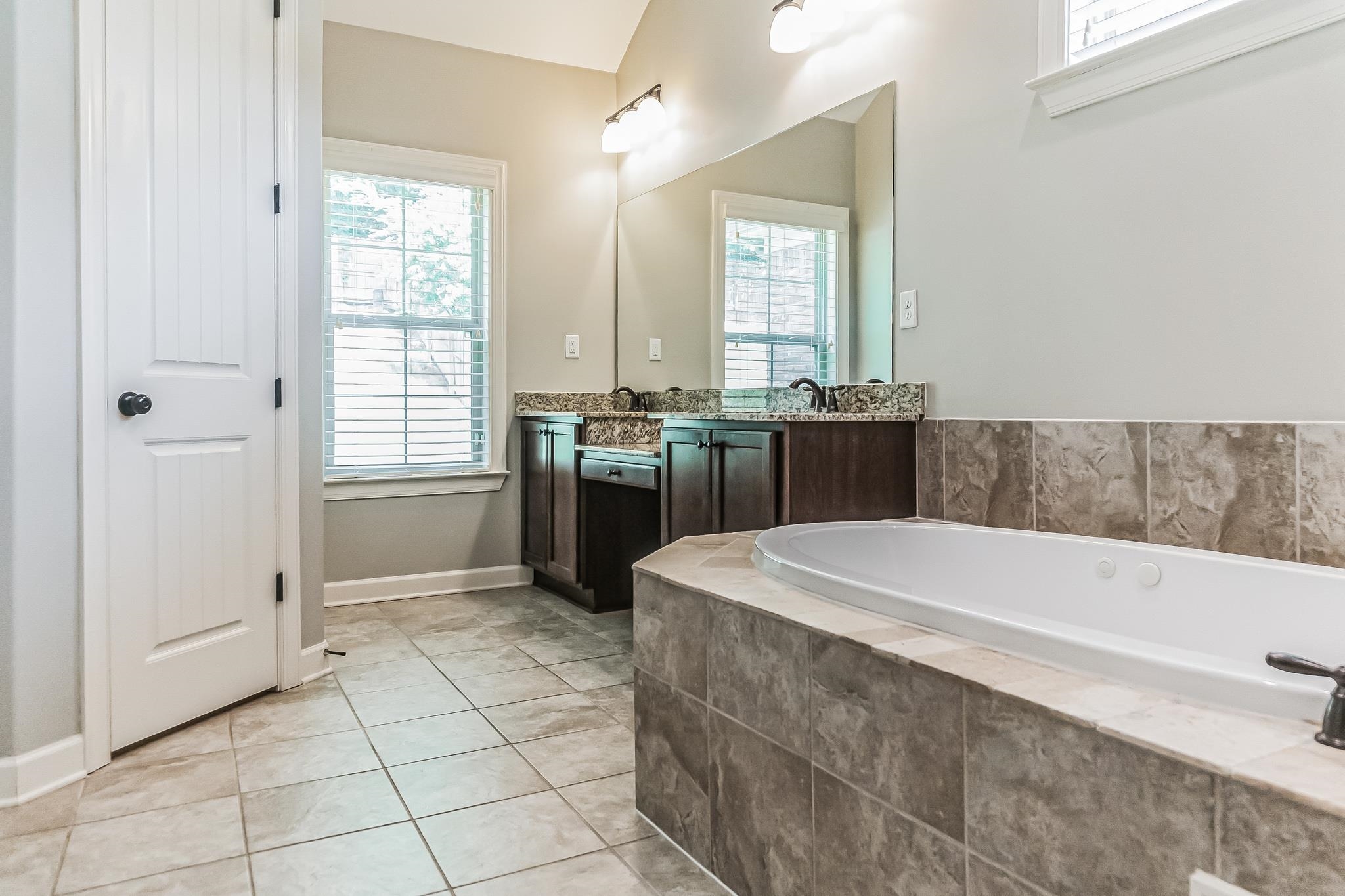 Bathroom featuring tiled bath, tile patterned floors, and vanity