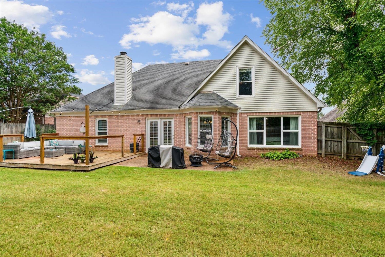 Rear view of house with a deck and a lawn