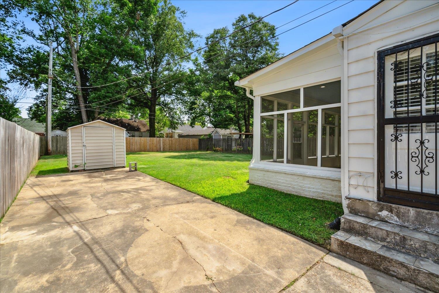 View of patio with a storage unit and a sunroom