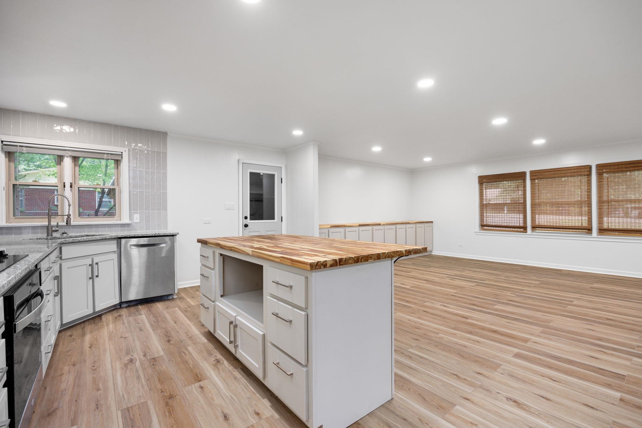 Kitchen featuring white cabinetry, stainless steel appliances, butcher block counters, a center island, and light hardwood / wood-style floors