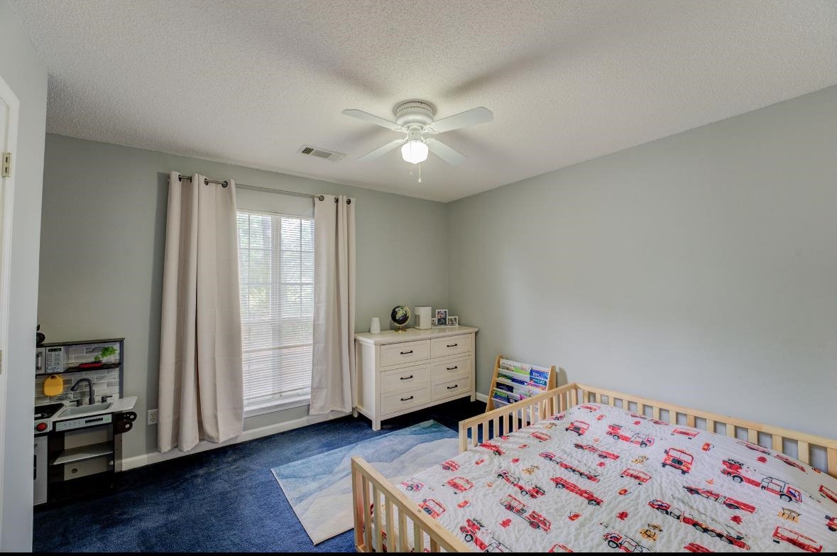 Carpeted bedroom featuring a textured ceiling and ceiling fan