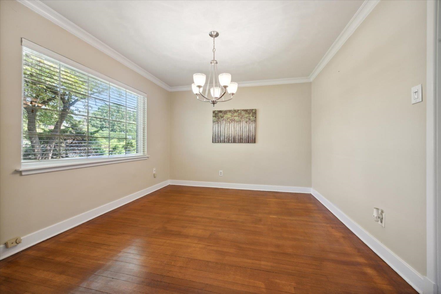 Unfurnished room with crown molding, dark wood-type flooring, and a chandelier