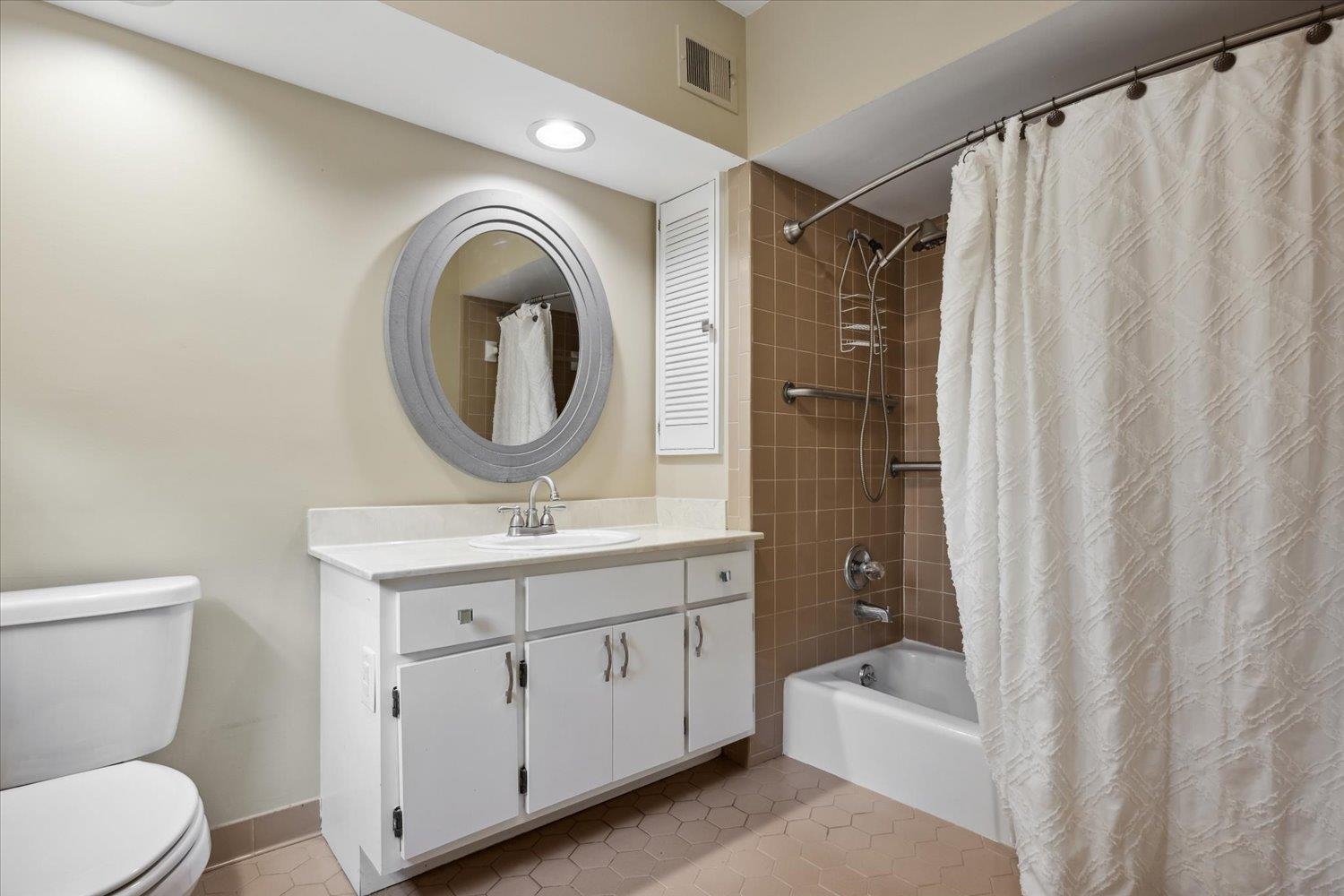 Full bathroom with vanity, shower / bath combo, tile patterned flooring, and toilet