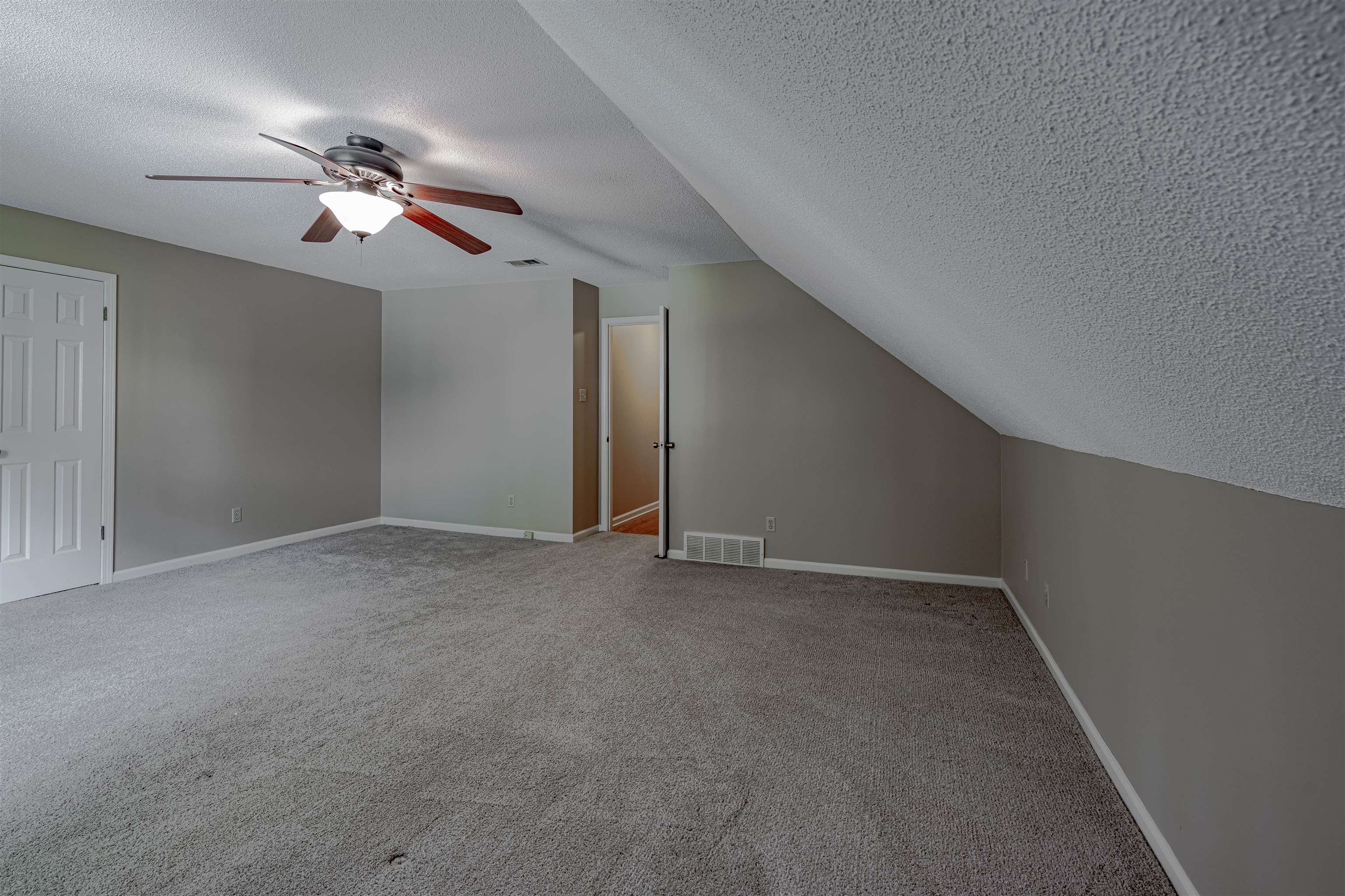 Bonus room featuring a textured ceiling, carpet flooring, lofted ceiling, and ceiling fan