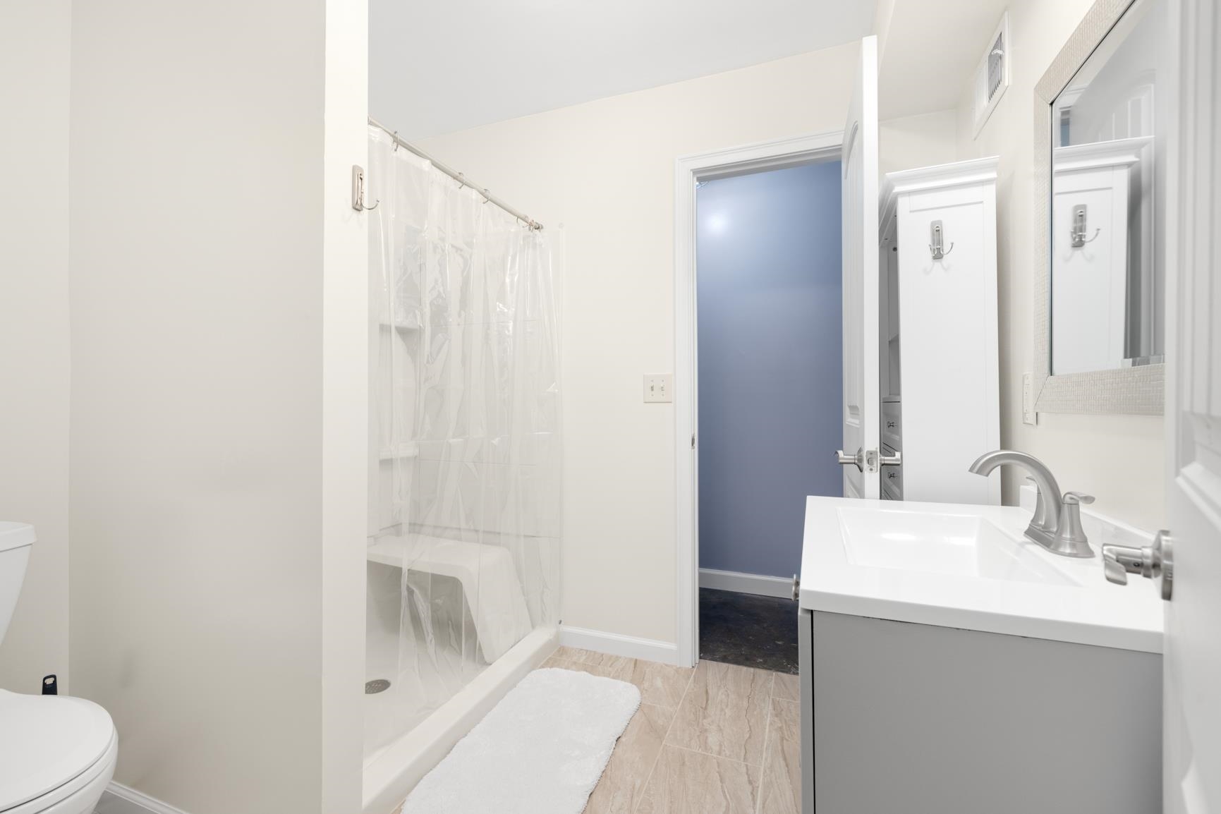 Bathroom with curtained shower, vanity, tile patterned floors, and toilet