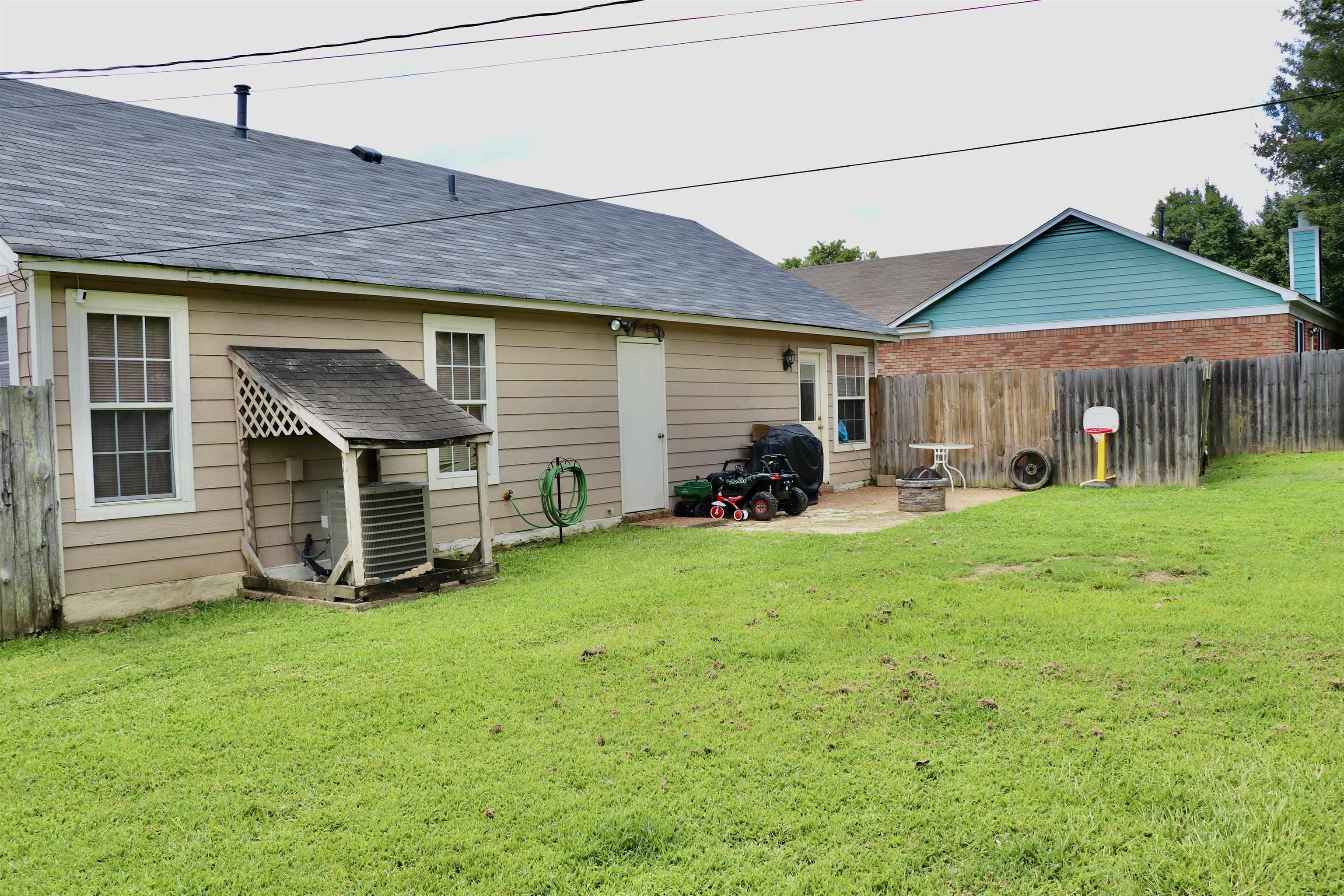 Back of property with central AC and a lawn