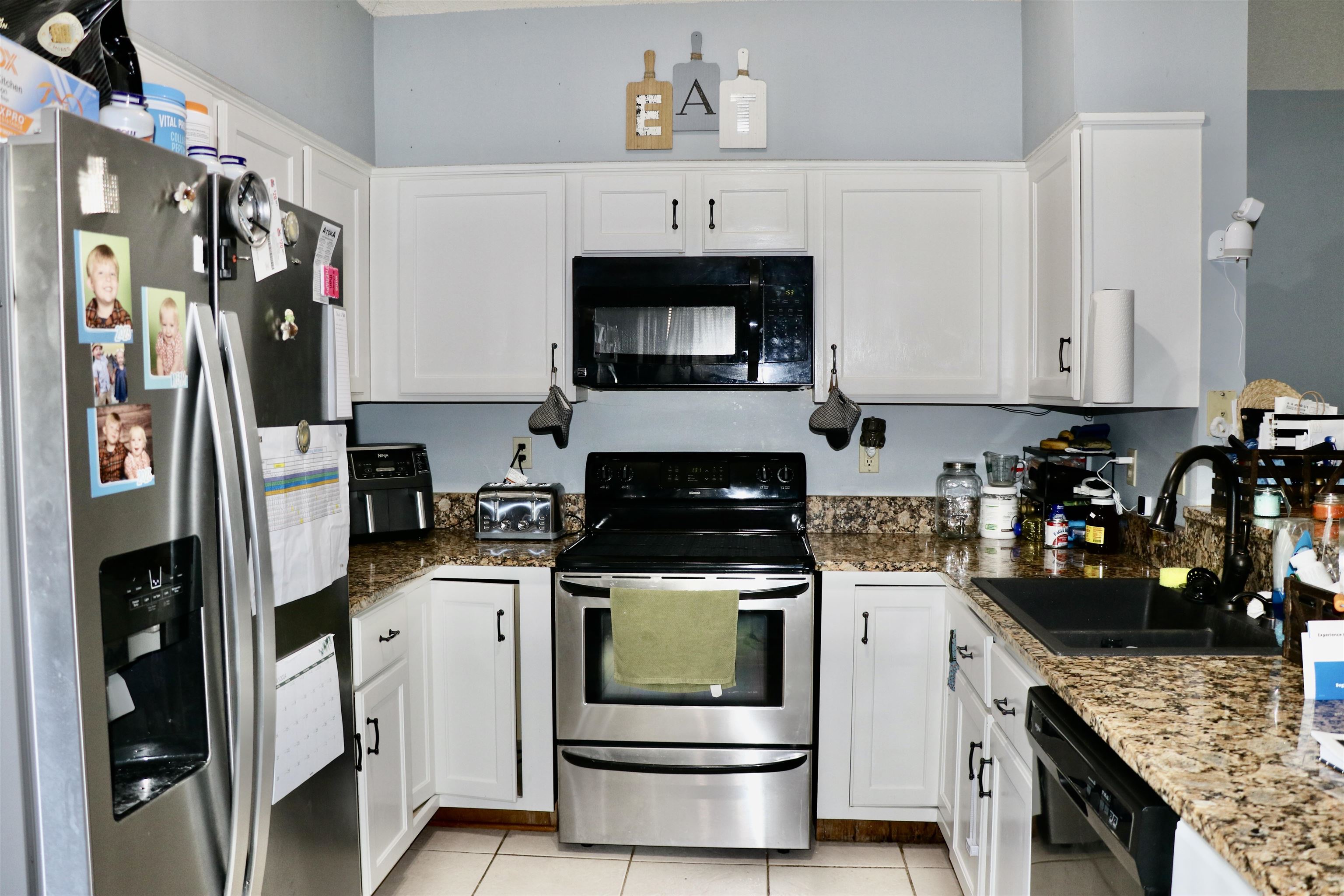 Kitchen with sink, white cabinetry, and black appliances