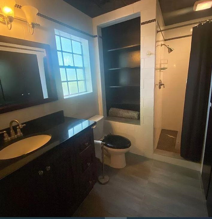 Bathroom with toilet, vanity, and a tile shower