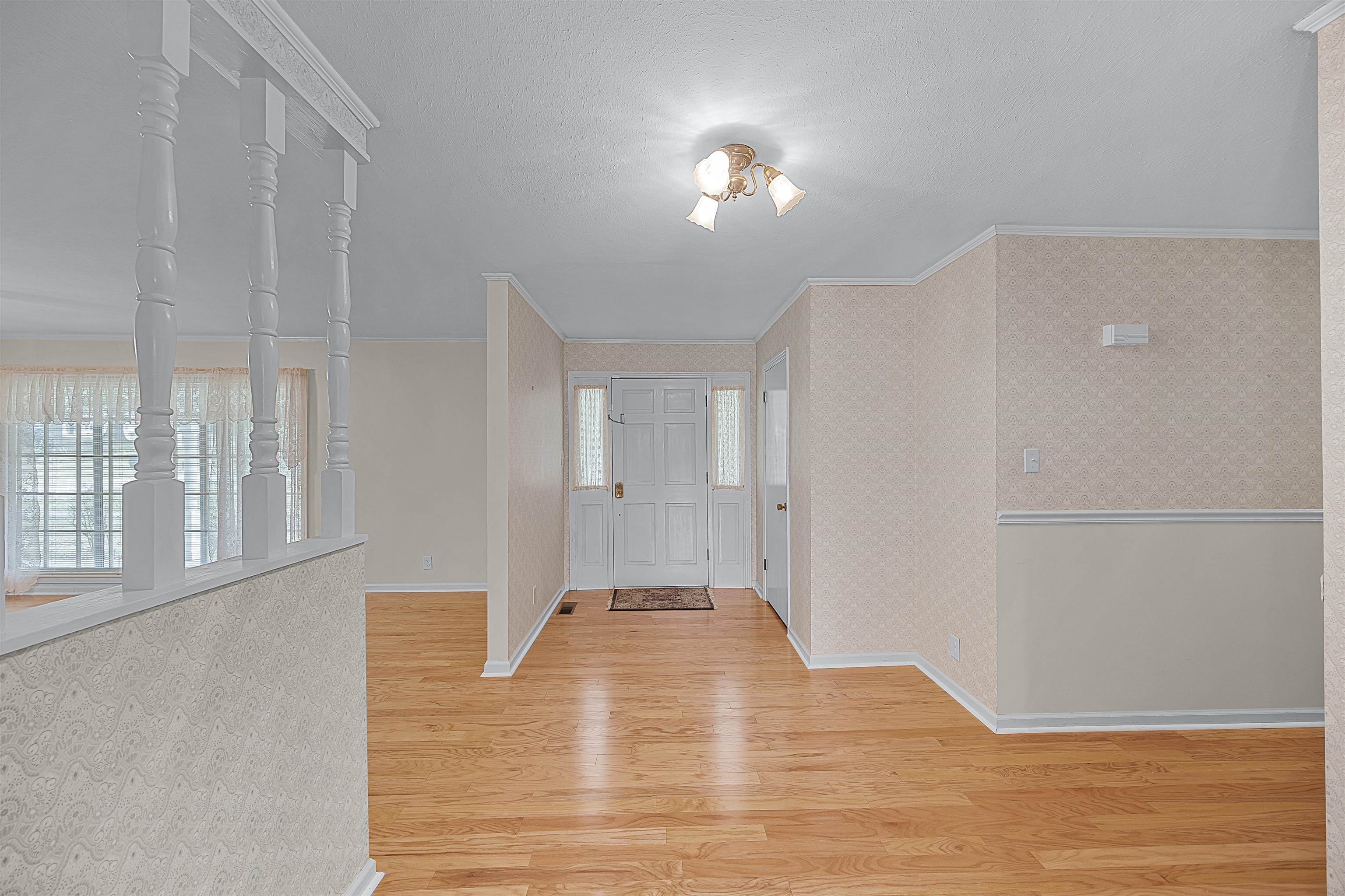 Foyer entrance featuring crown molding and light wood-type flooring