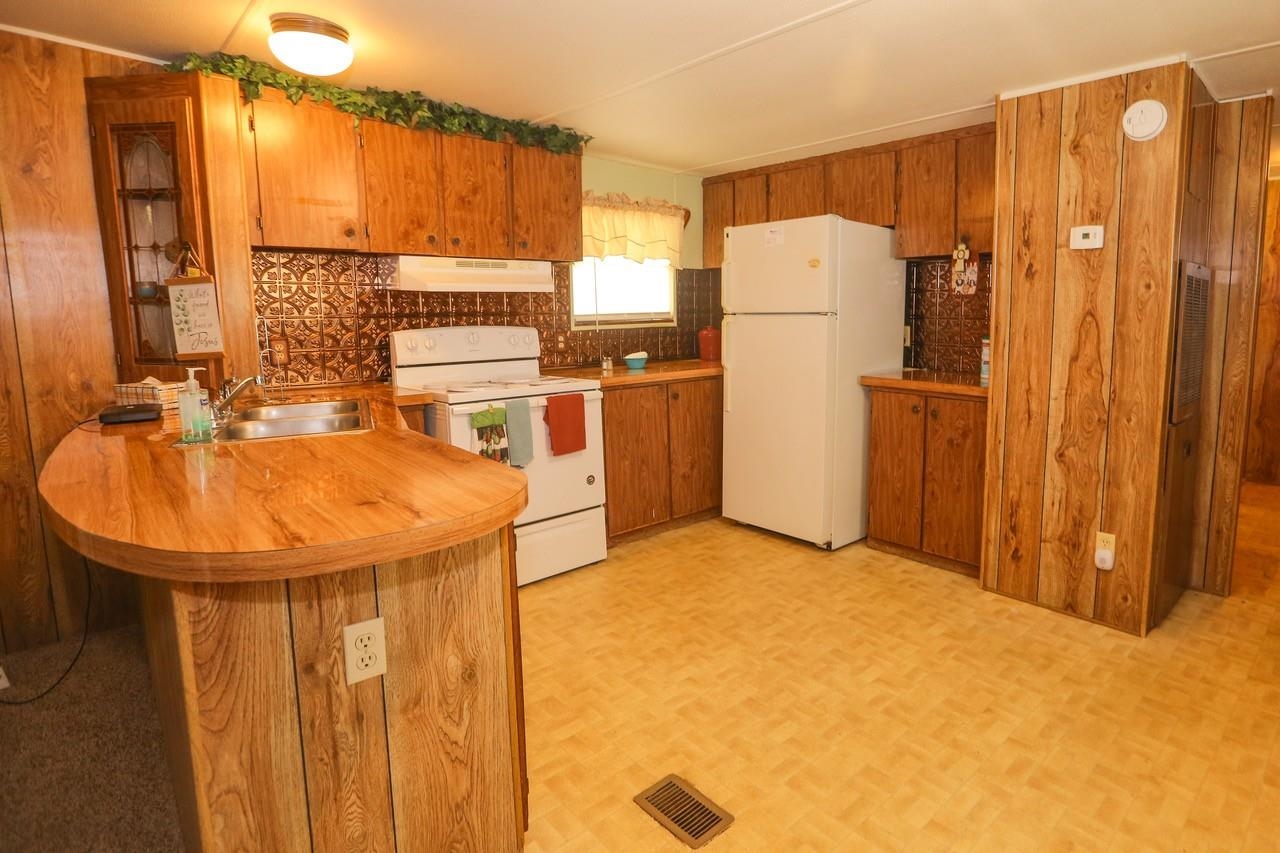 Kitchen featuring tasteful backsplash, white appliances, light parquet floors, wall chimney exhaust hood, and sink