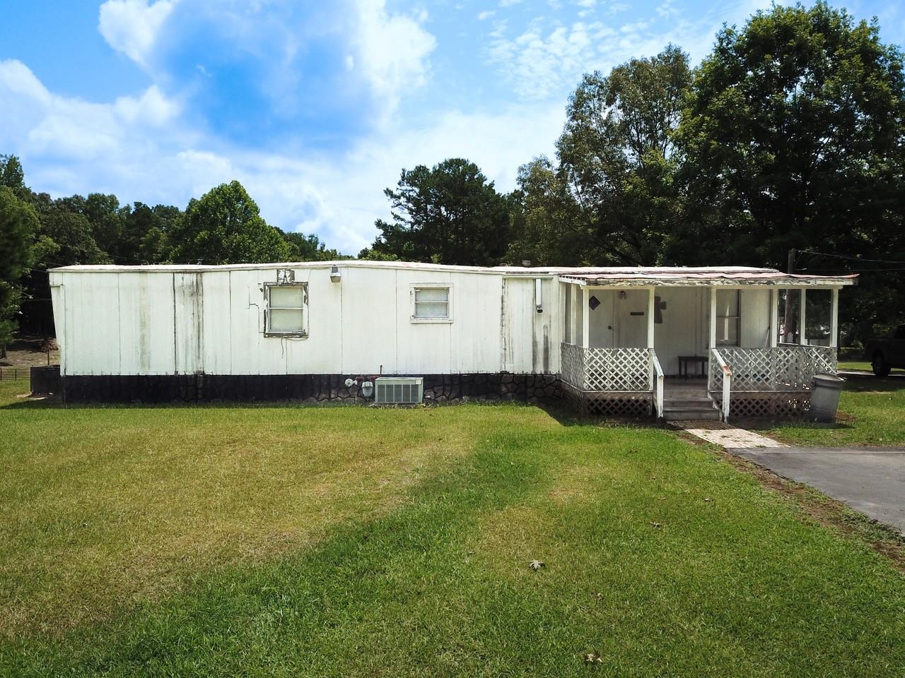 Manufactured / mobile home featuring covered porch, cooling unit, and a front yard