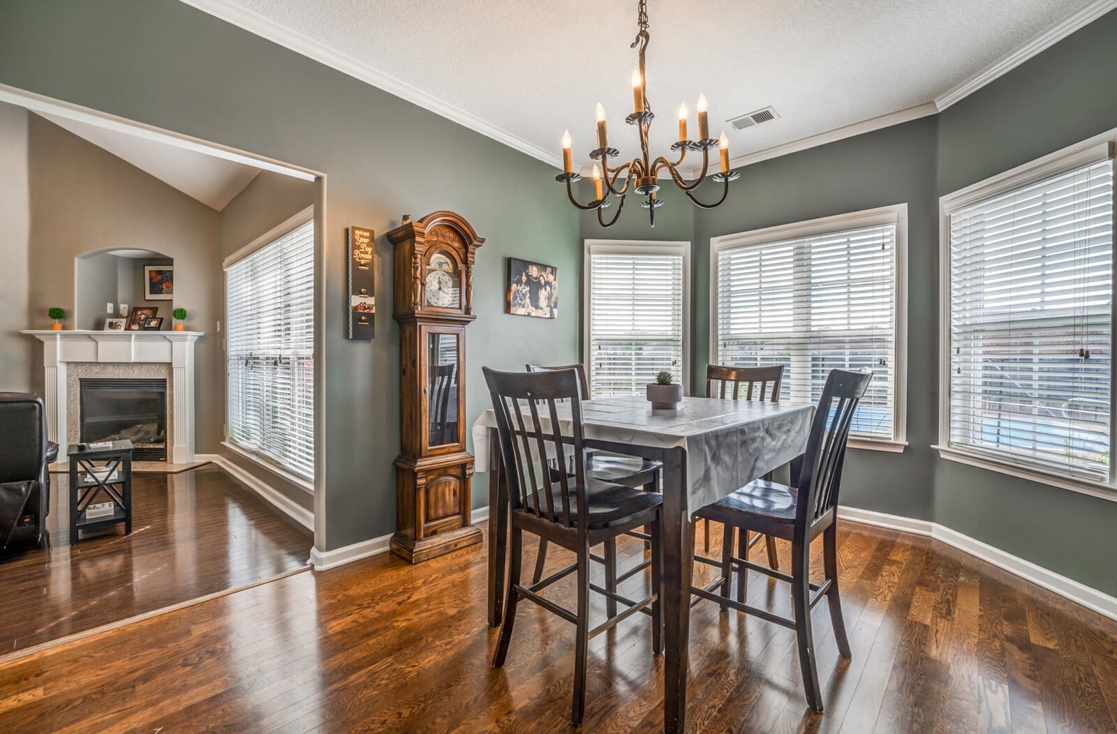 Dining area featuring dark wood-type flooring, crown molding, a notable chandelier, and a wealth of natural light