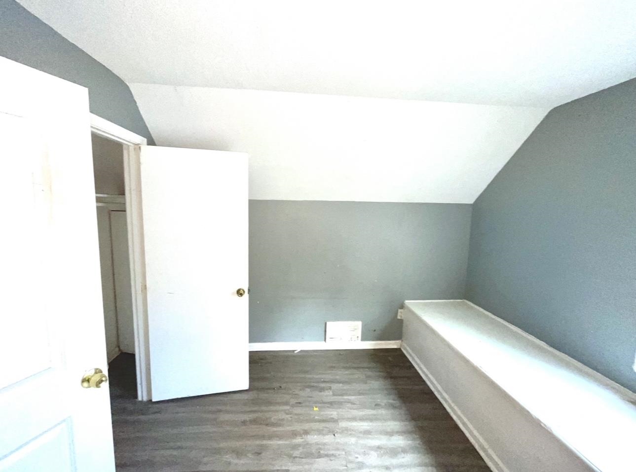 Bonus room with dark hardwood / wood-style flooring and vaulted ceiling