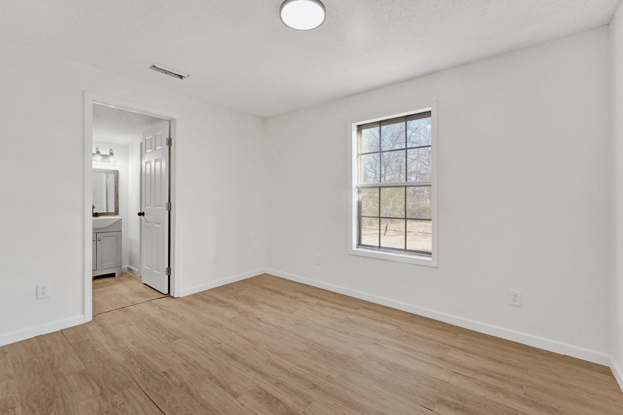 Unfurnished bedroom featuring light hardwood / wood-style flooring and connected bathroom