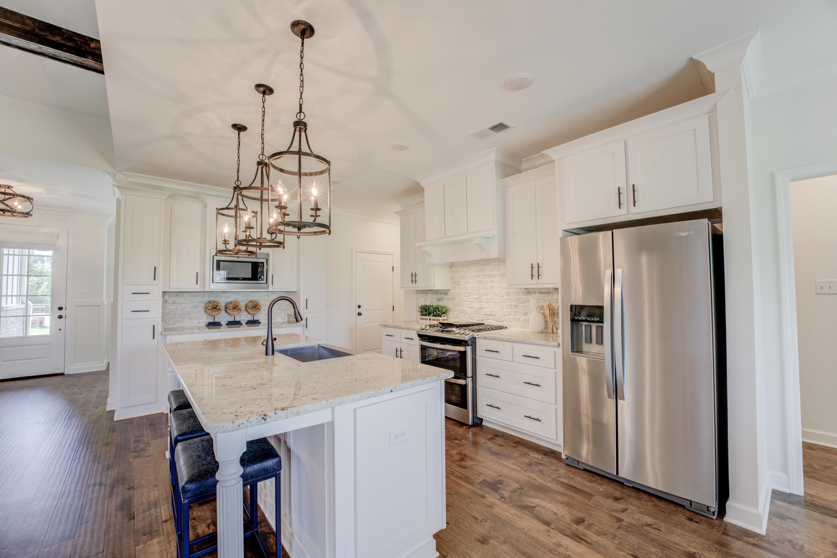 Kitchen with white cabinetry, tasteful backsplash, appliances with stainless steel finishes, hardwood / wood-style flooring, and sink