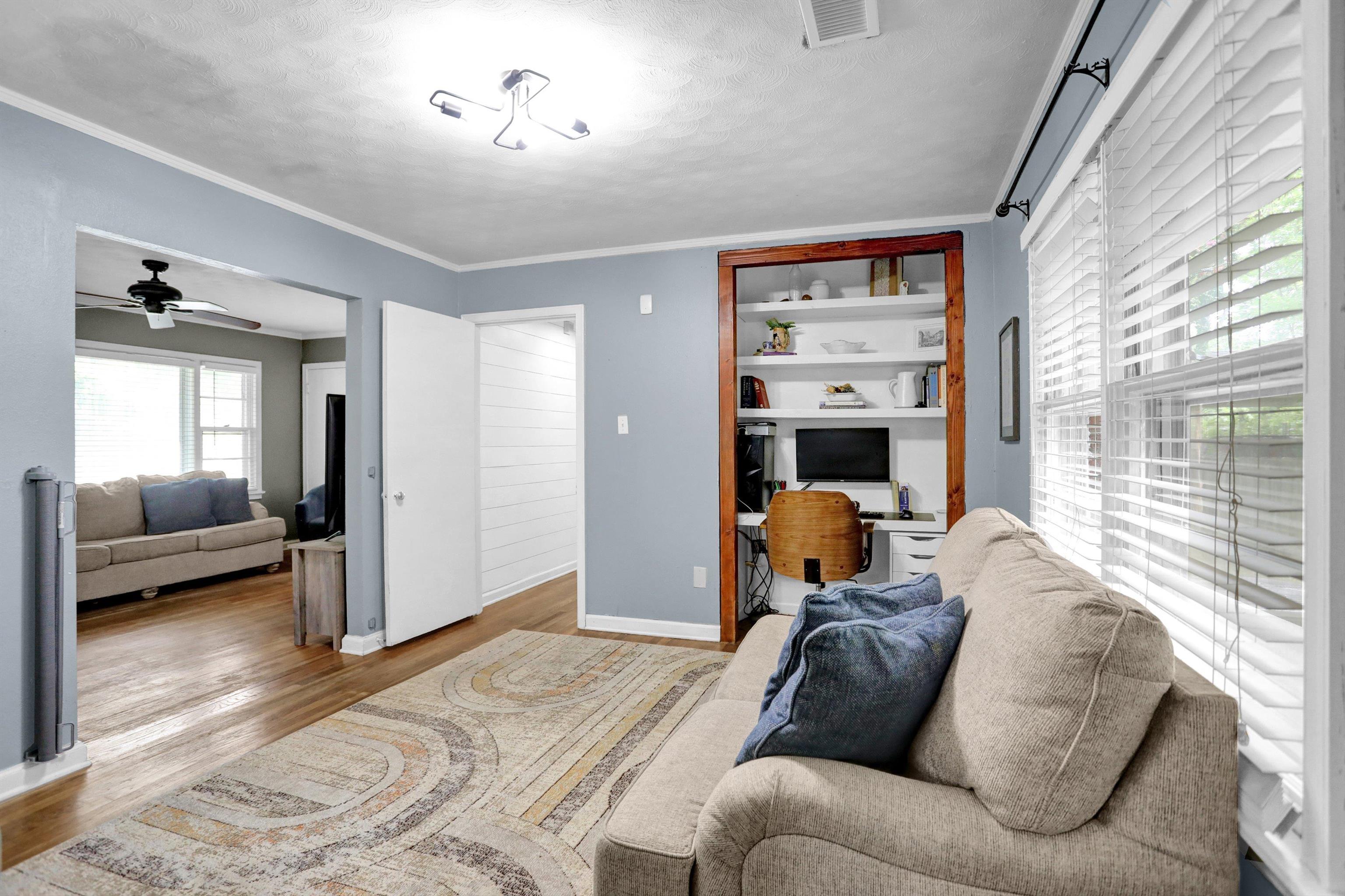 Living room with crown molding, light wood-type flooring, and ceiling fan