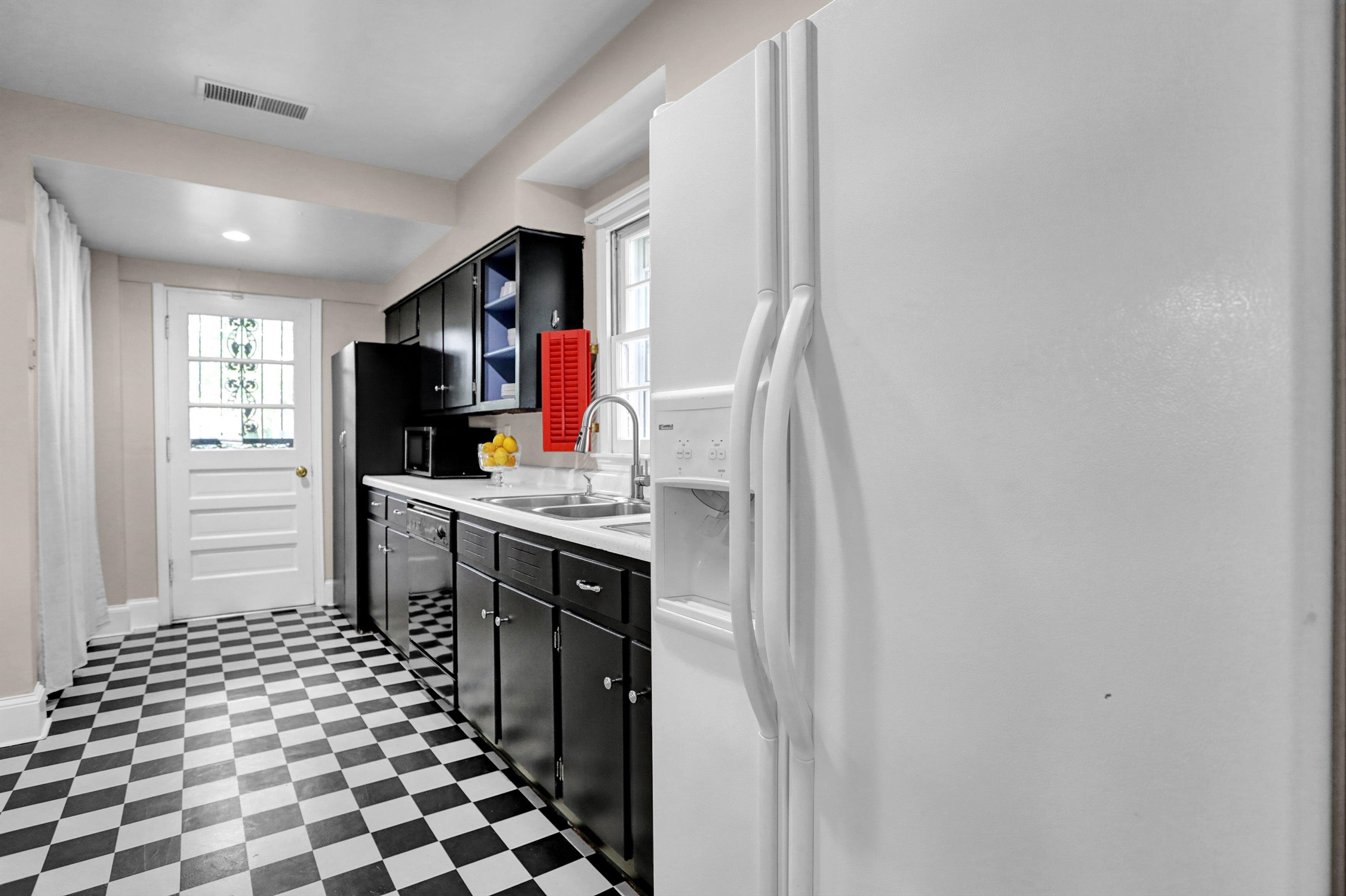 Kitchen featuring sink, white fridge with ice dispenser, dishwasher, and dark tile patterned flooring