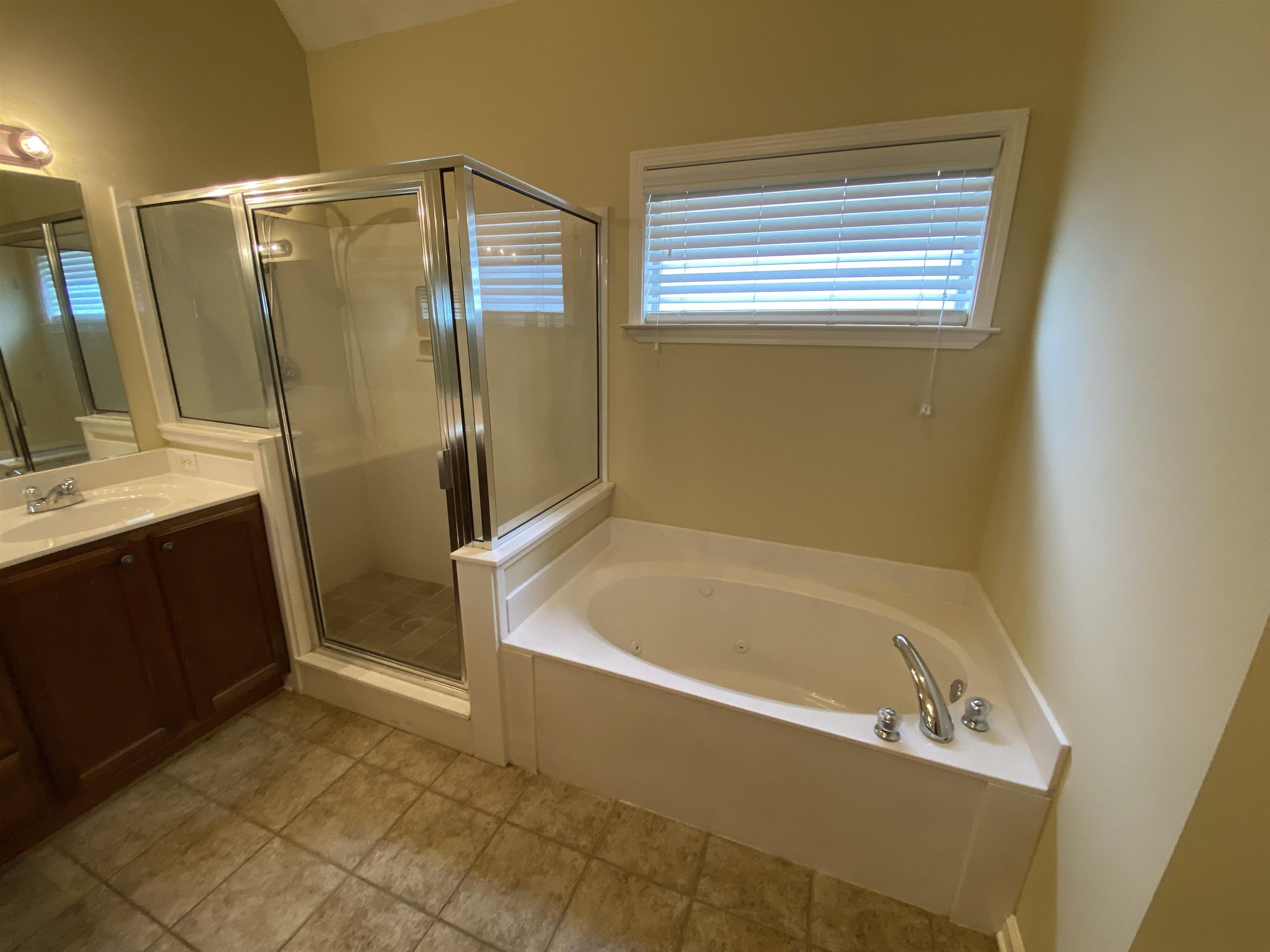 Bathroom featuring plus walk in shower, vanity, and tile patterned flooring