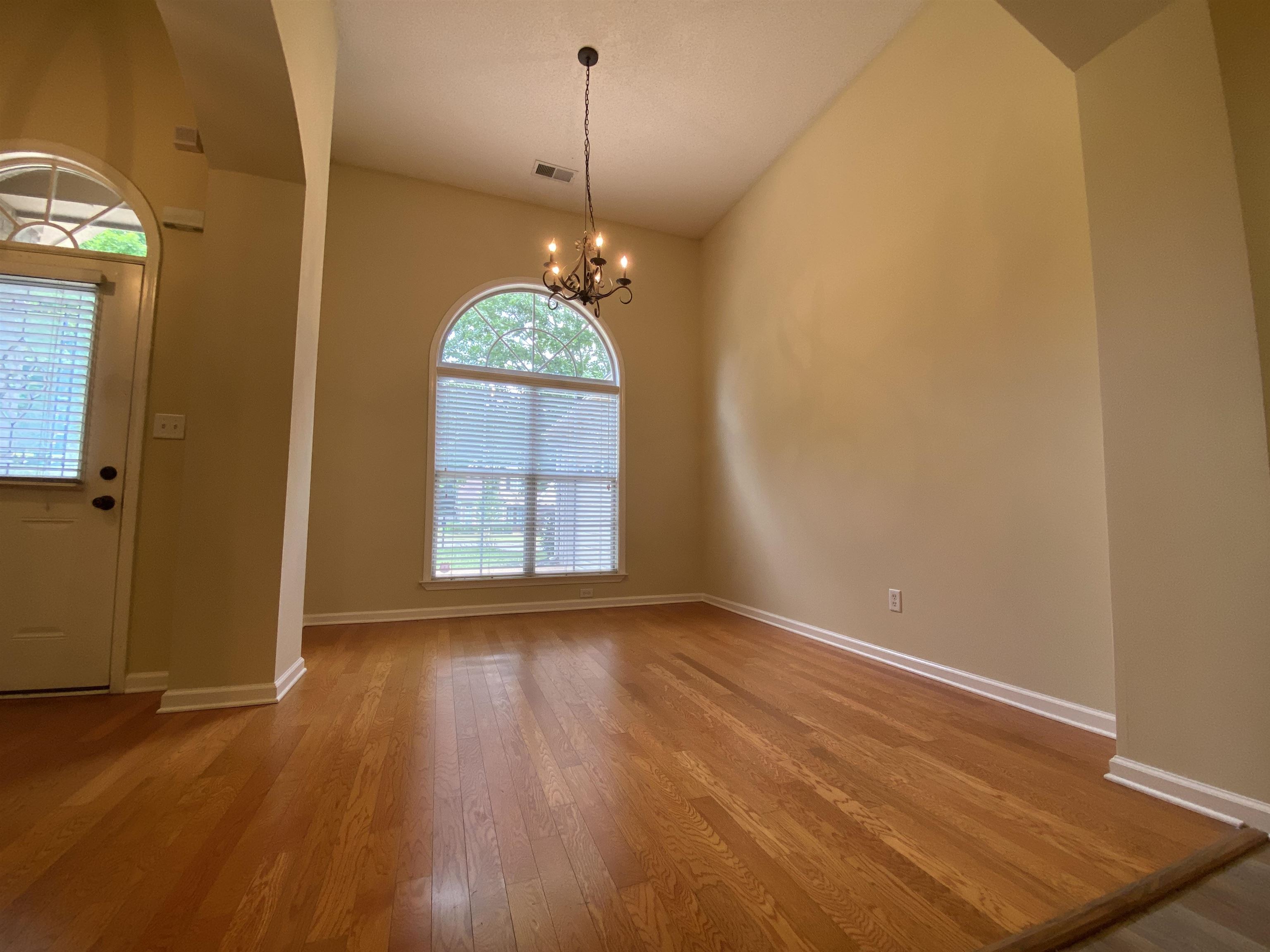 Entrance foyer featuring an inviting chandelier, wood-type flooring, and lofted ceiling