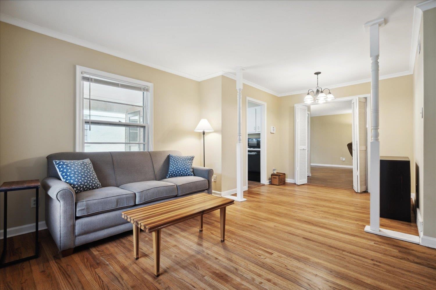 Living room featuring a notable chandelier, crown molding, and light wood-type flooring