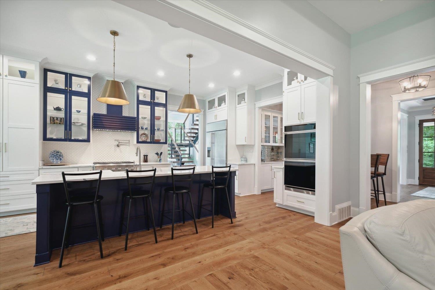 Kitchen featuring decorative backsplash, black double oven, light hardwood / wood-style flooring, and white cabinets