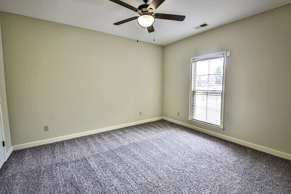 Carpeted empty room featuring ceiling fan