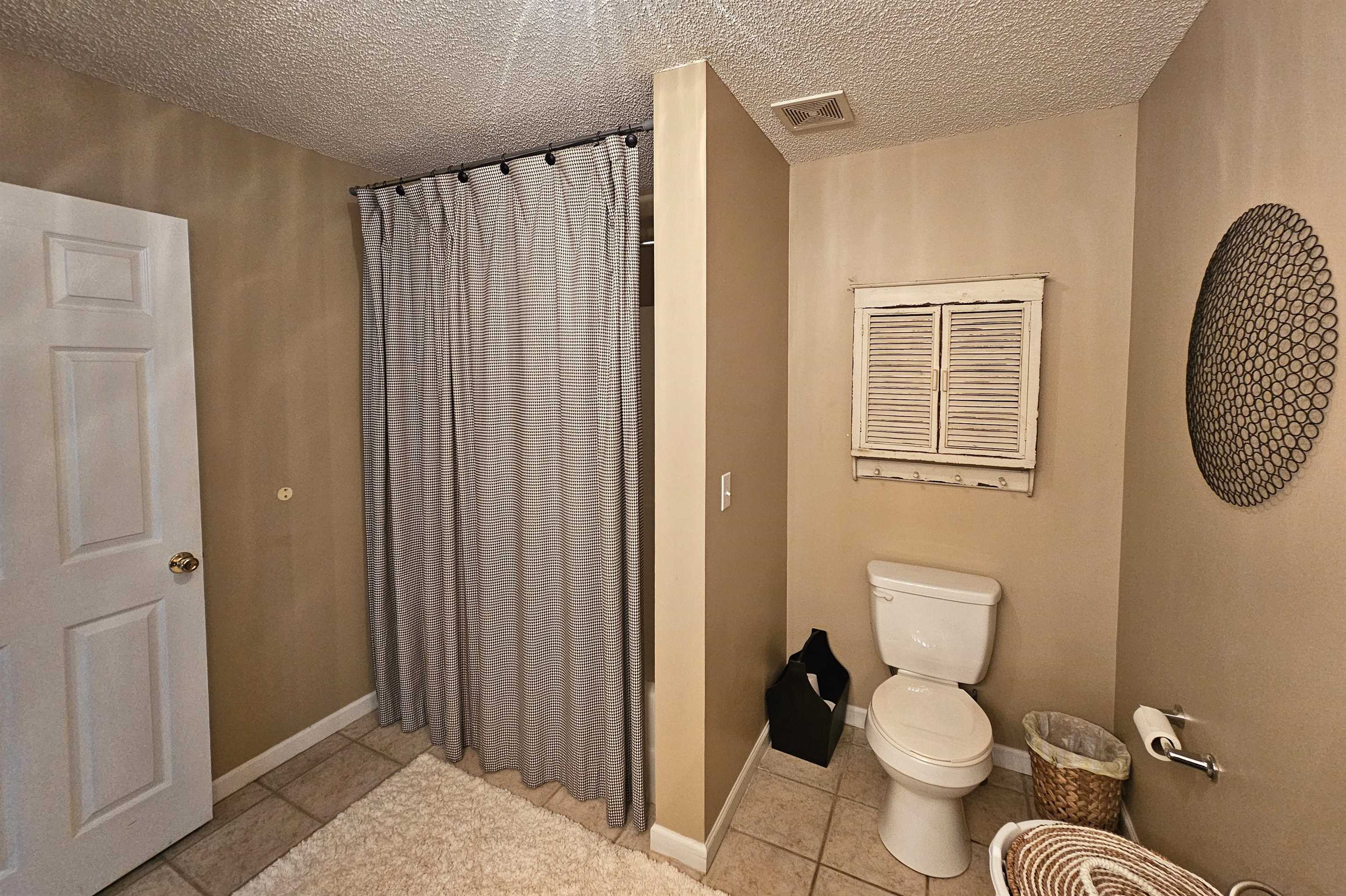 Bathroom with tile patterned floors, a textured ceiling, and toilet