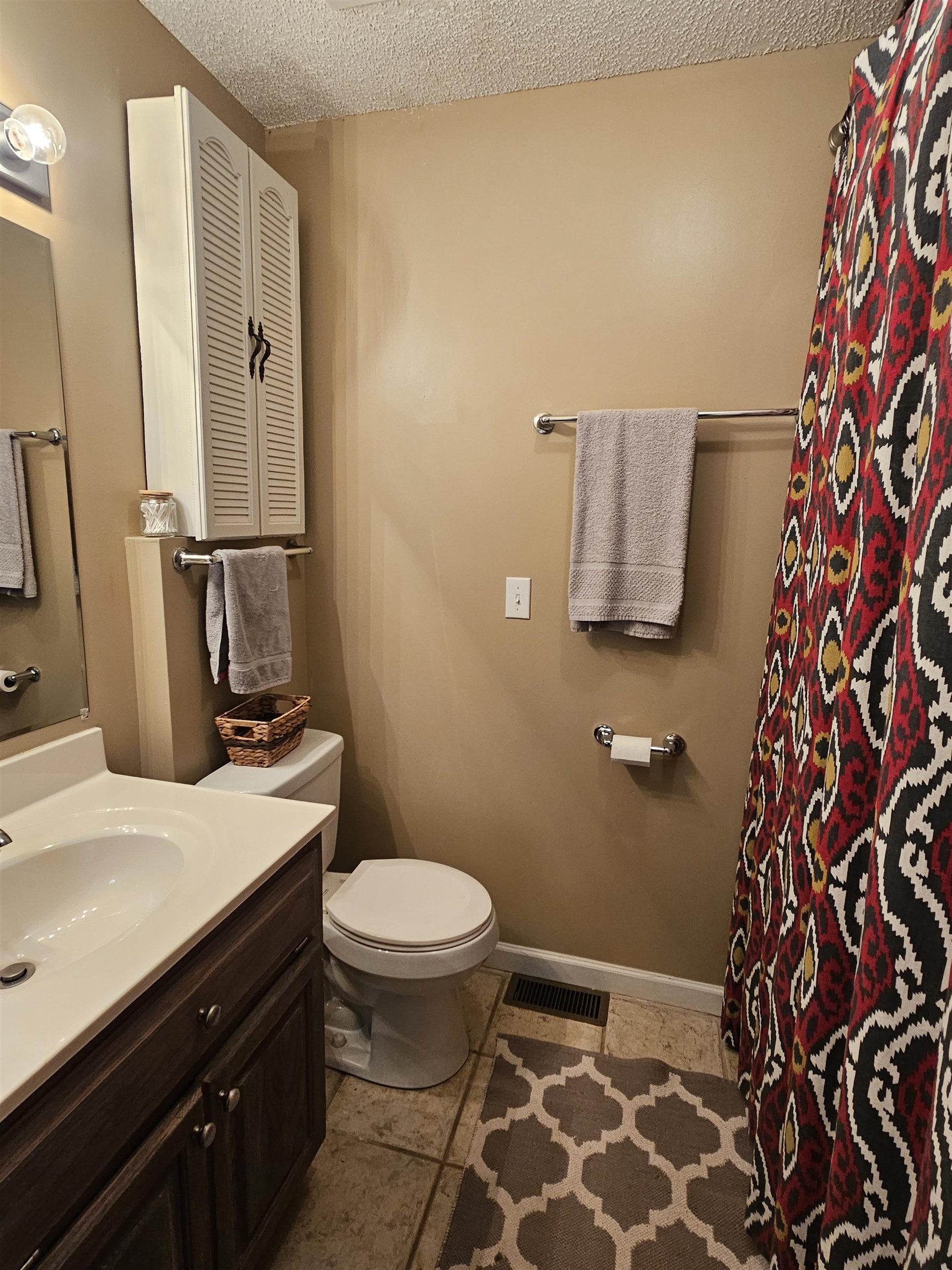 Bathroom featuring vanity, toilet, a textured ceiling, and tile patterned flooring