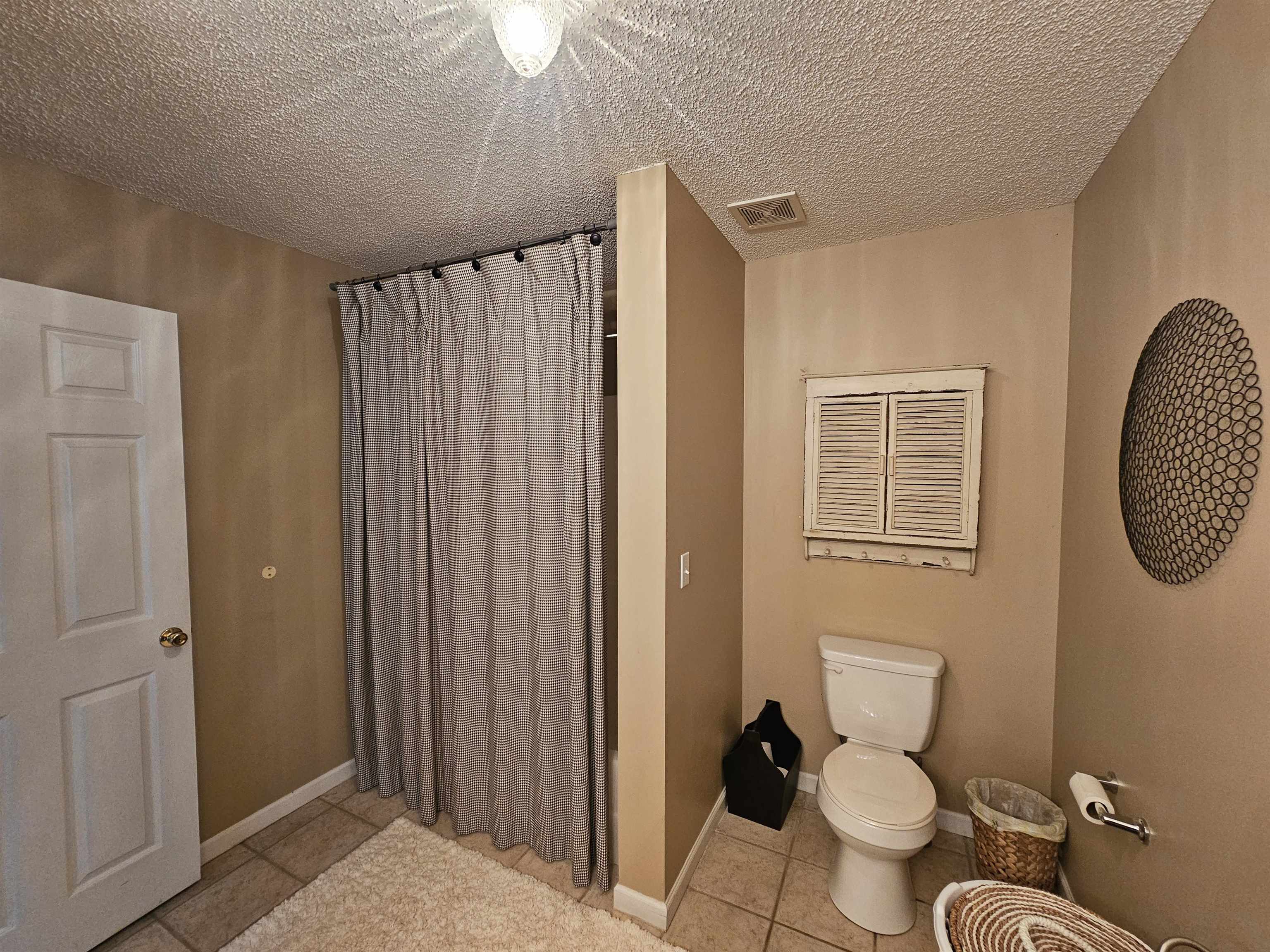 Bathroom featuring tile patterned flooring, toilet, and a textured ceiling