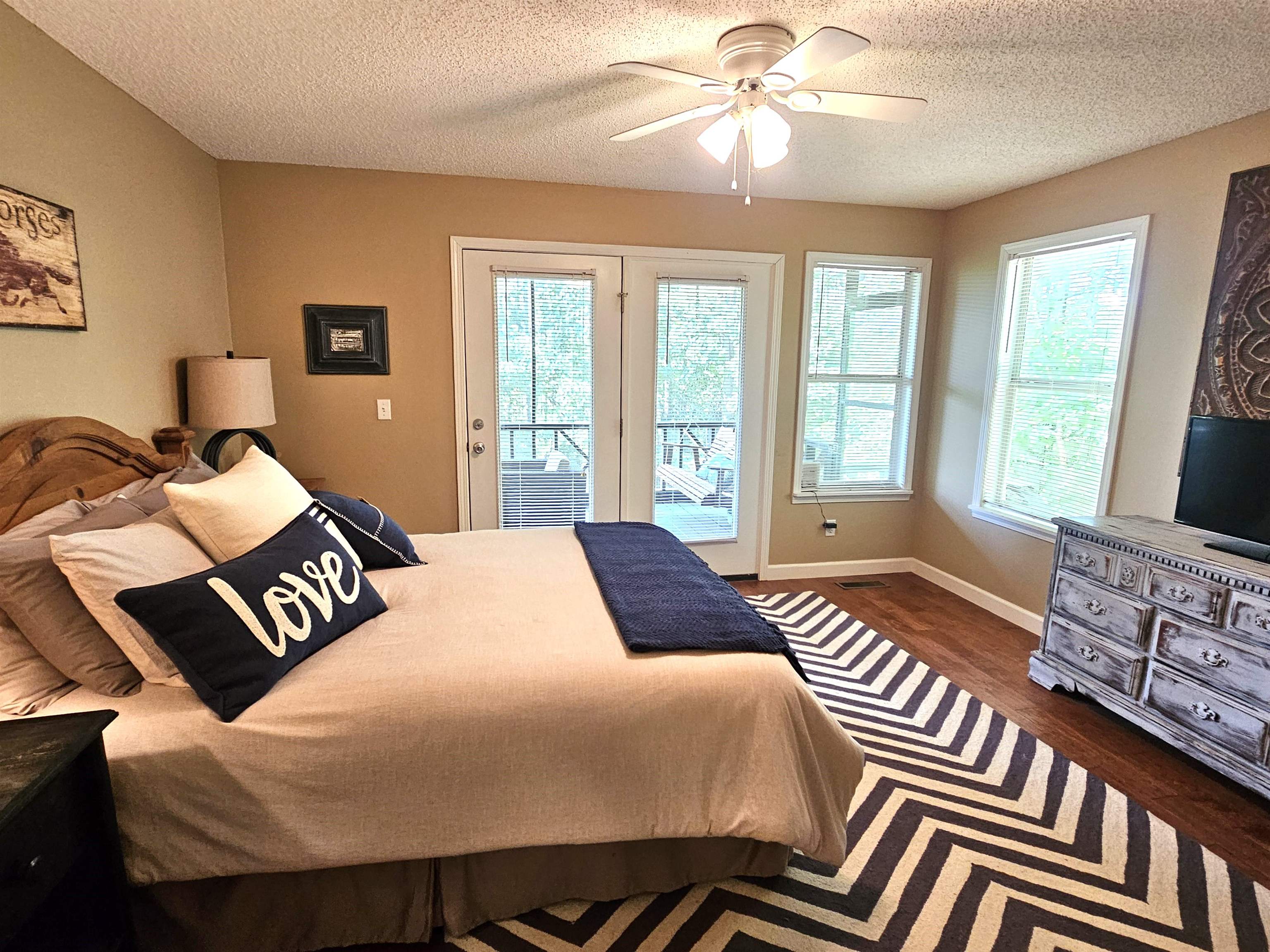 Bedroom with dark hardwood / wood-style floors, a textured ceiling, access to exterior, and ceiling fan