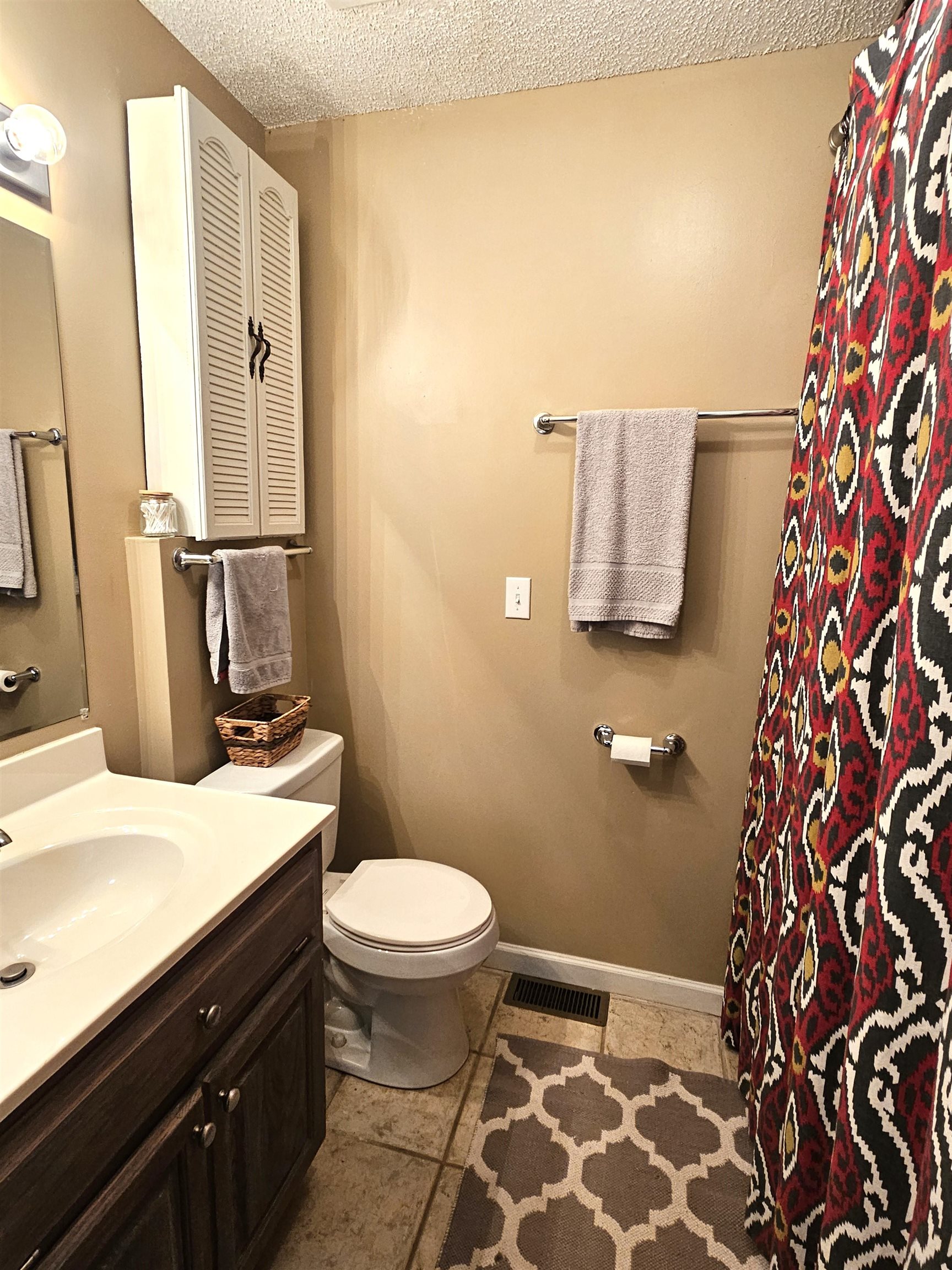 Bathroom with vanity, tile patterned floors, a textured ceiling, and toilet