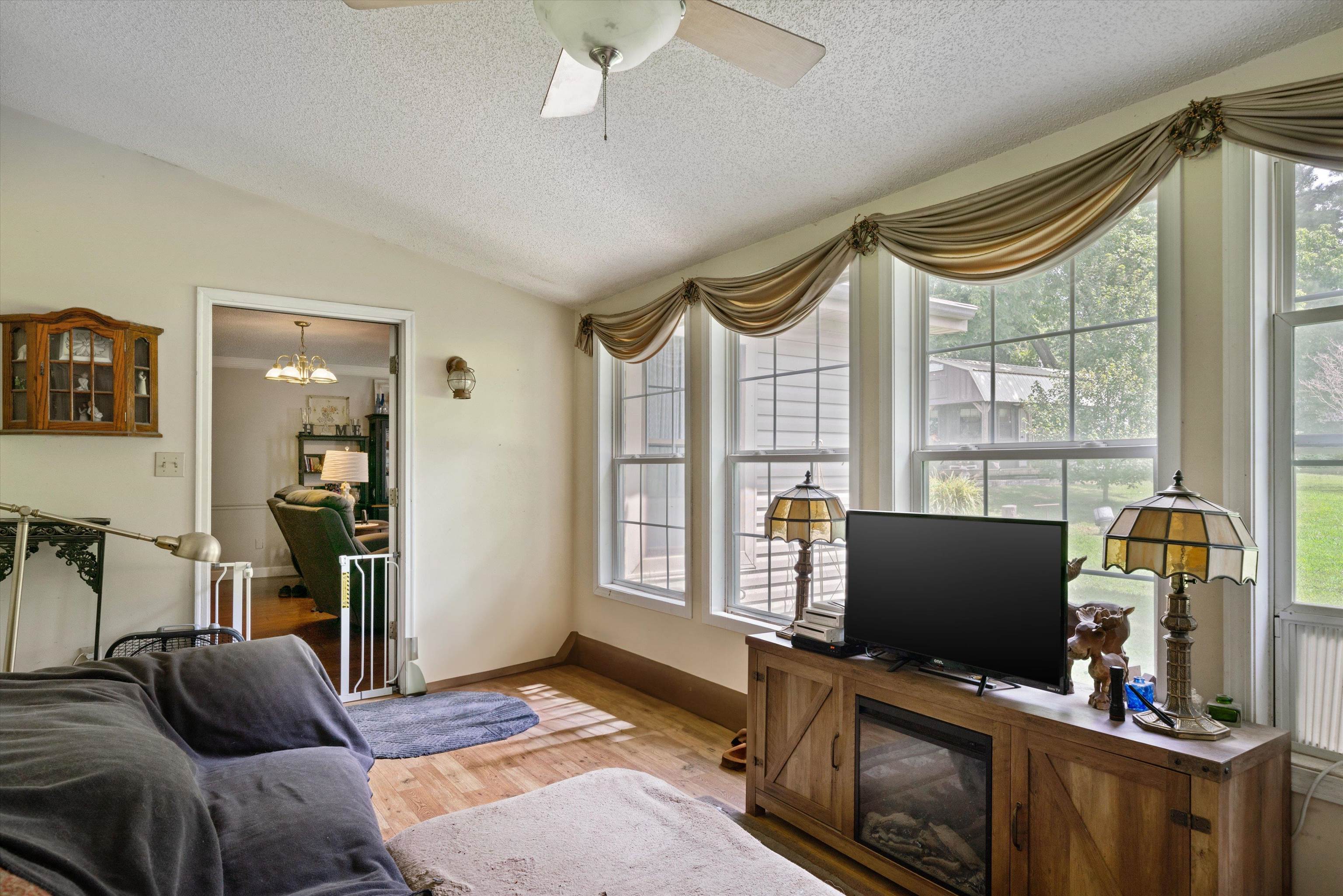 Sunroom featuring plenty of natural light, ceiling fan with notable chandelier, a textured ceiling, and hardwood / wood-style flooring