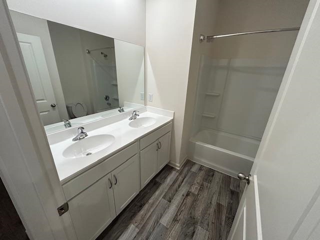 Full bathroom featuring shower / bathtub combination, double vanity, toilet, and hardwood / wood-style floors