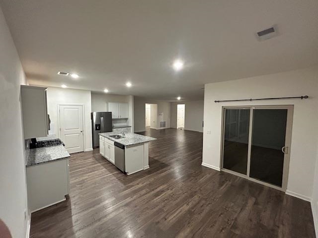 Kitchen featuring light stone countertops, dark hardwood / wood-style flooring, appliances with stainless steel finishes, and a kitchen island