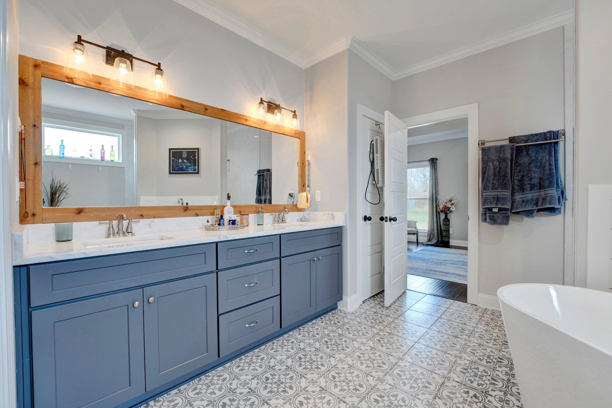 Bathroom featuring tile patterned floors, double sink vanity, a bathing tub, and crown molding