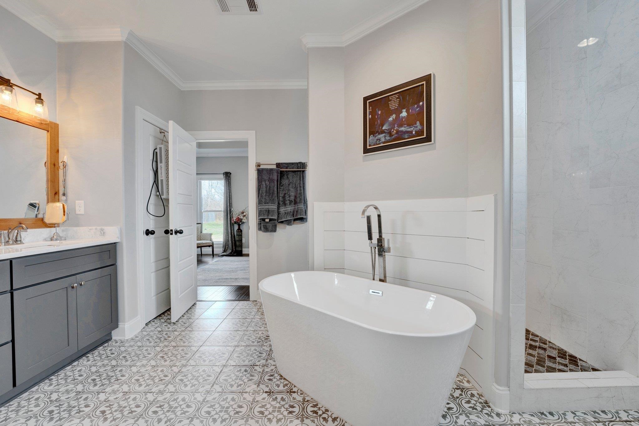 Bathroom with tile patterned flooring, tile walls, vanity, crown molding, and shower with separate bathtub