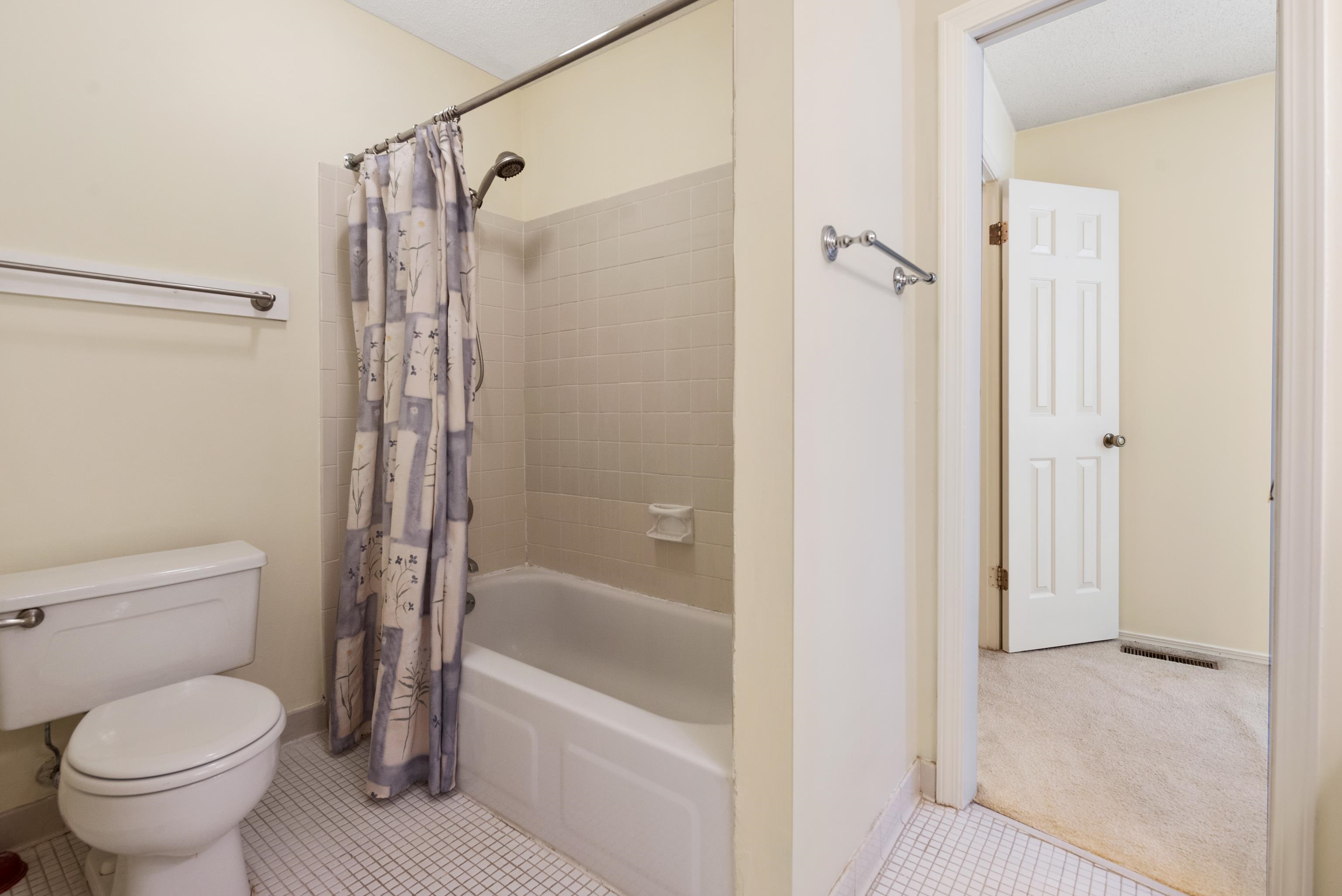 Primary bathroom with shower / tub combo with curtain, tile patterned flooring, and toilet