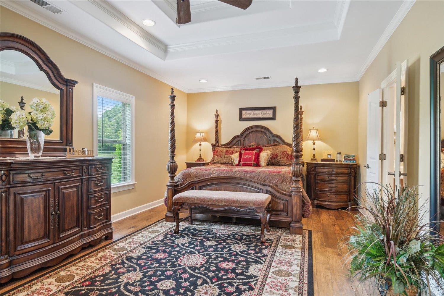 Bedroom featuring a tray ceiling, light wood-type flooring, and ornamental molding