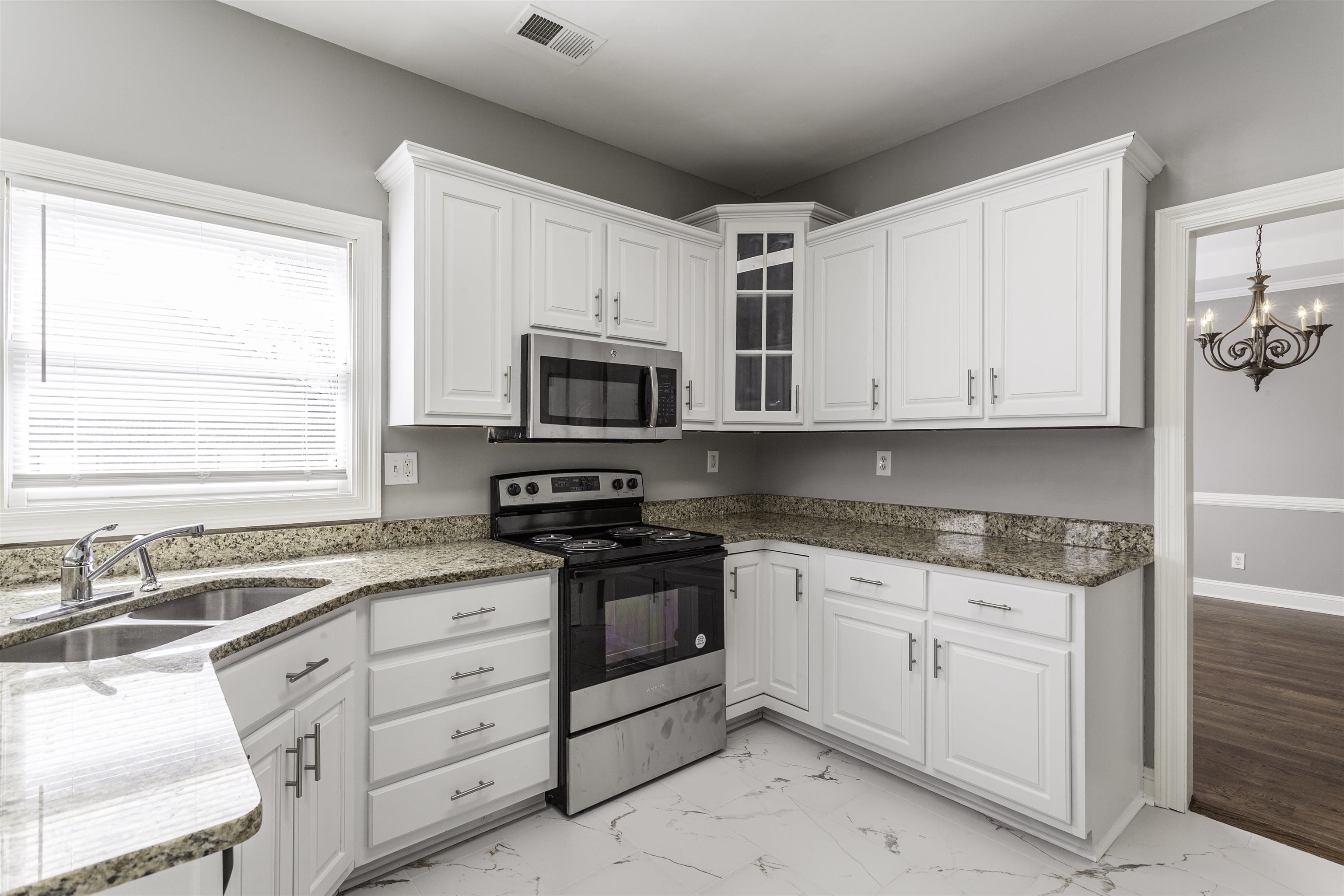 Kitchen with sink, appliances with stainless steel finishes, light hardwood / wood-style floors, and white cabinetry