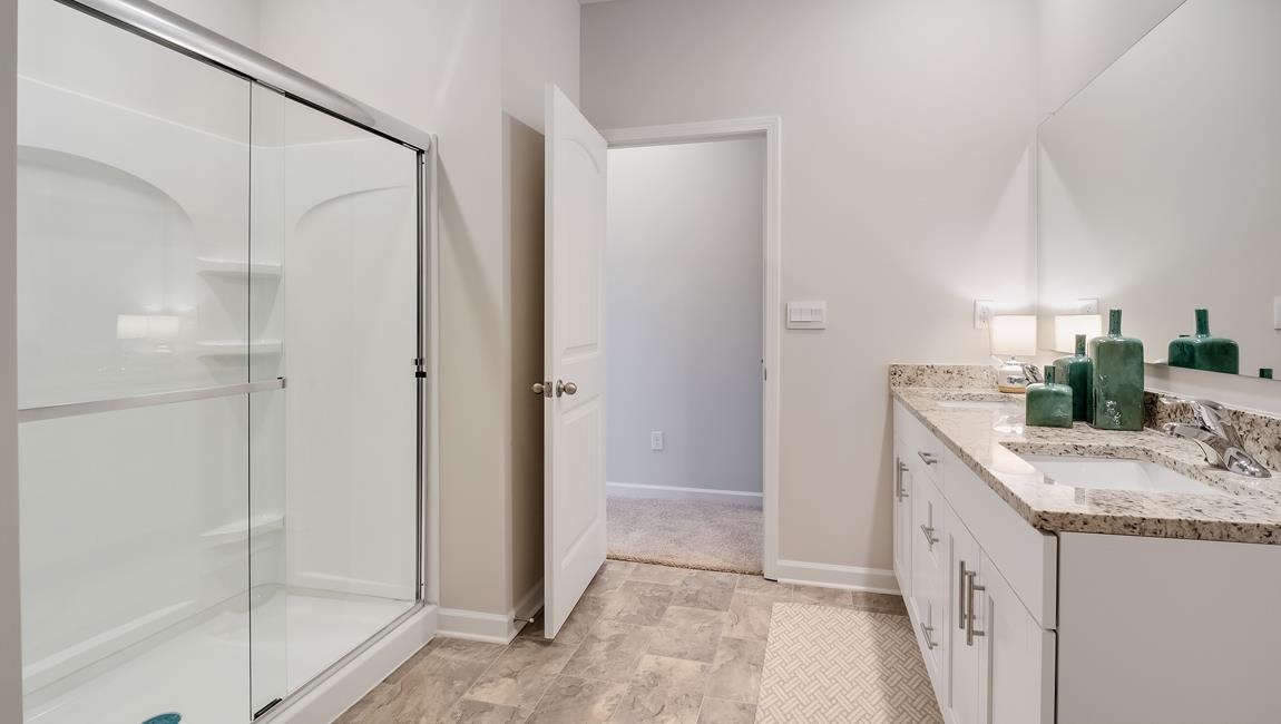 Bathroom with tile patterned floors, double sink vanity, and an enclosed shower