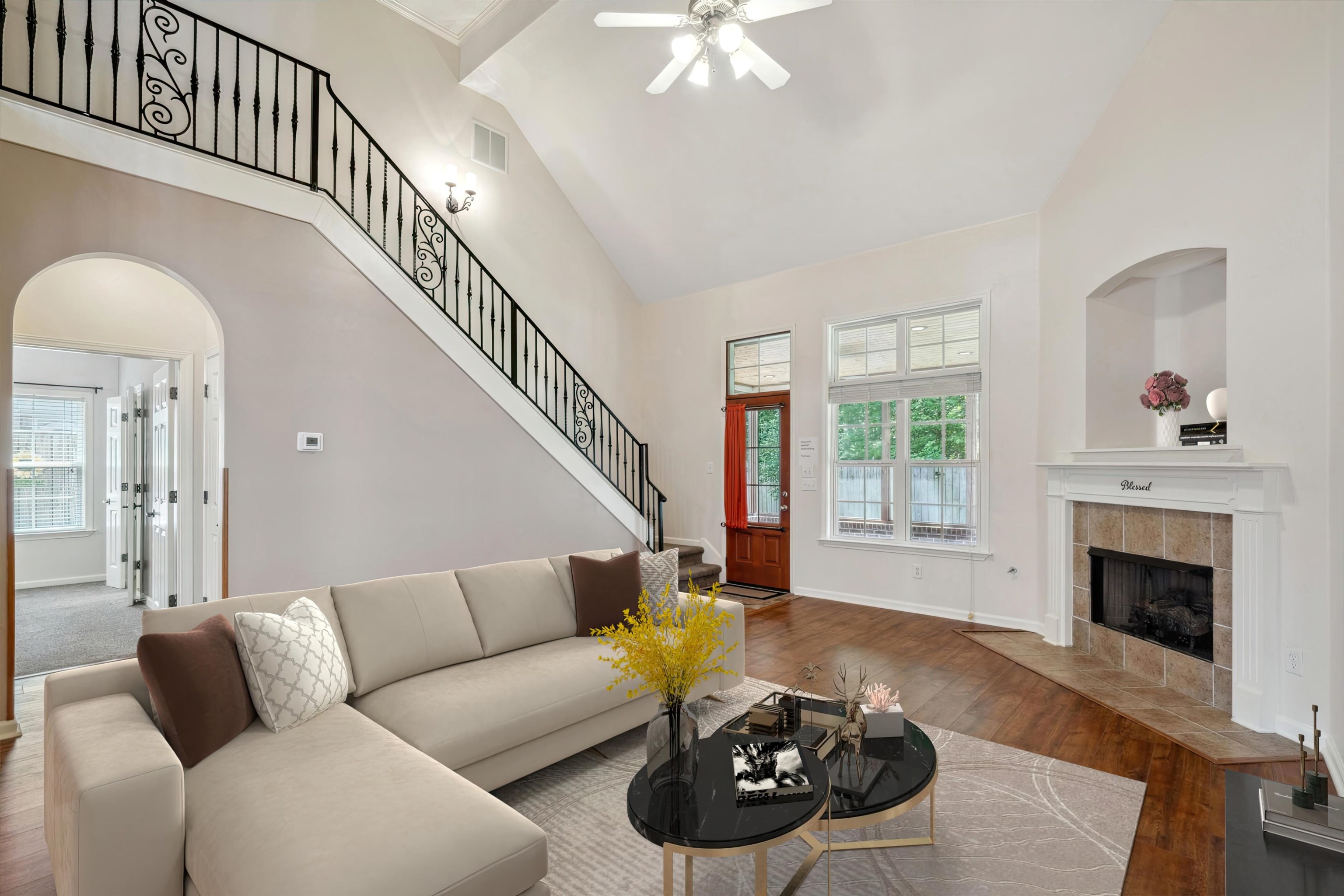 Living room with a tiled fireplace, hardwood / wood-style floors, high vaulted ceiling, and ceiling fan