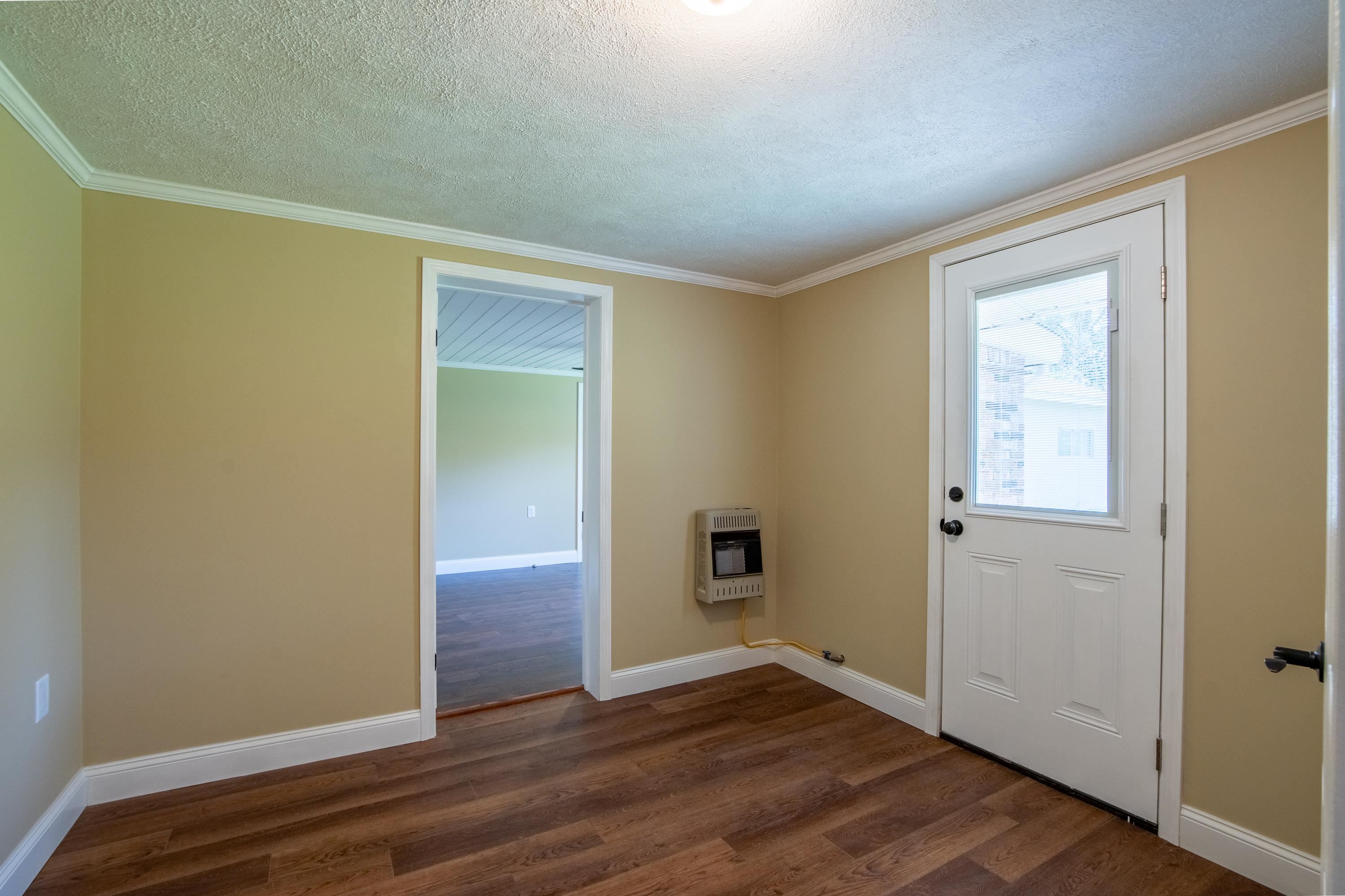 Doorway to outside with a textured ceiling, hardwood / wood-style flooring, and ornamental molding