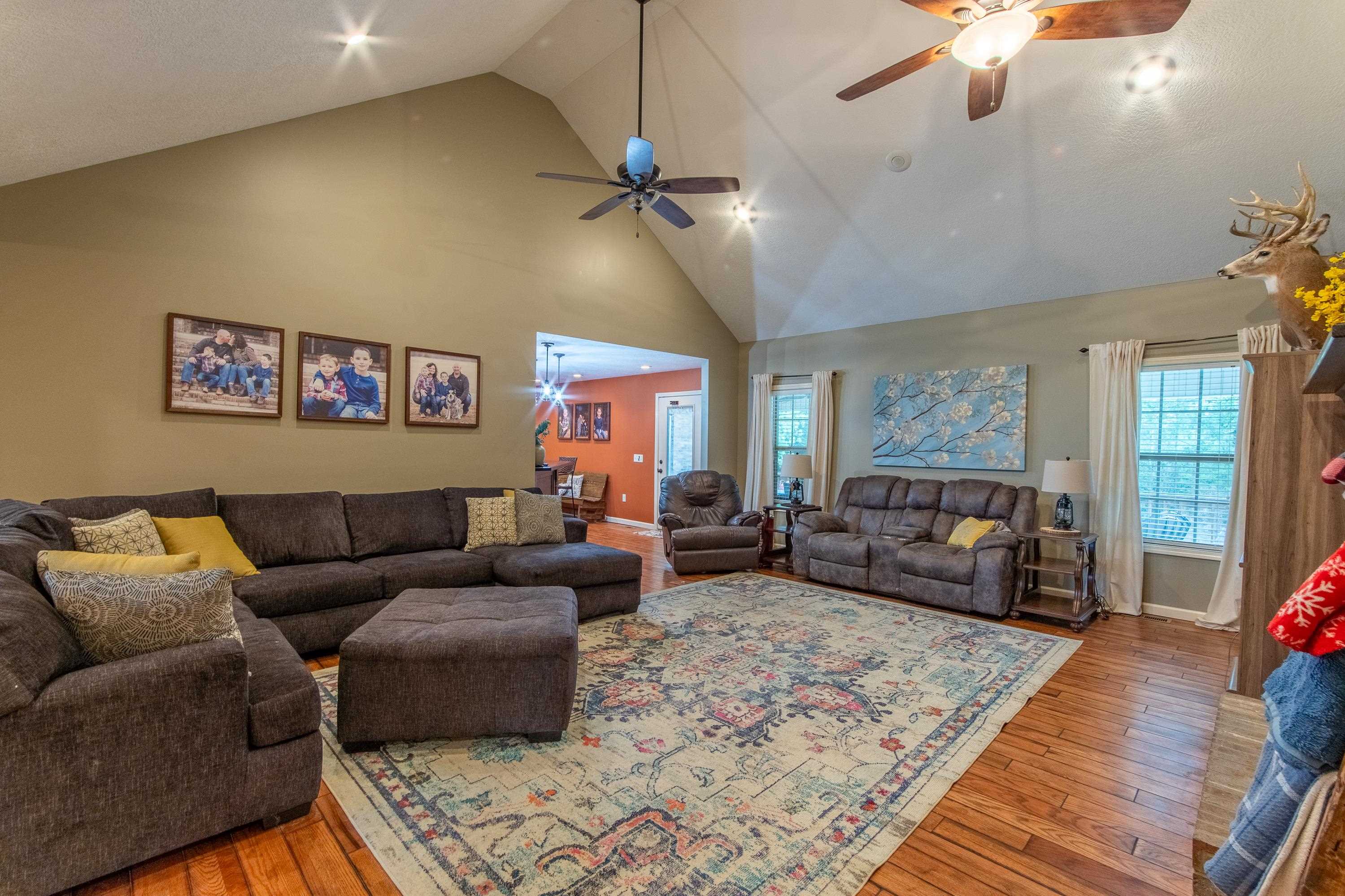 Living room featuring high vaulted ceiling, ceiling fan, and hardwood / wood-style floors