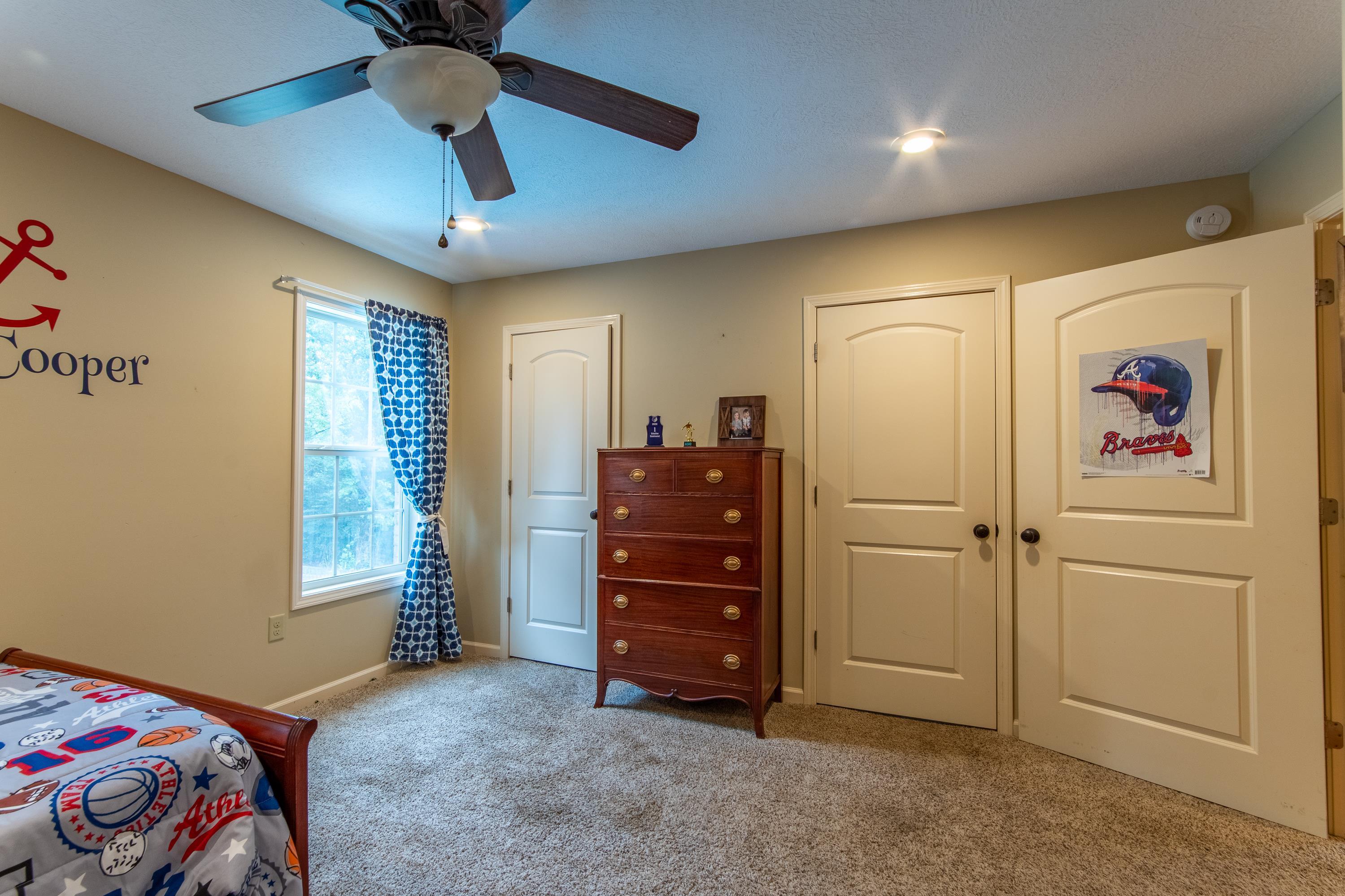 Carpeted bedroom featuring ceiling fan